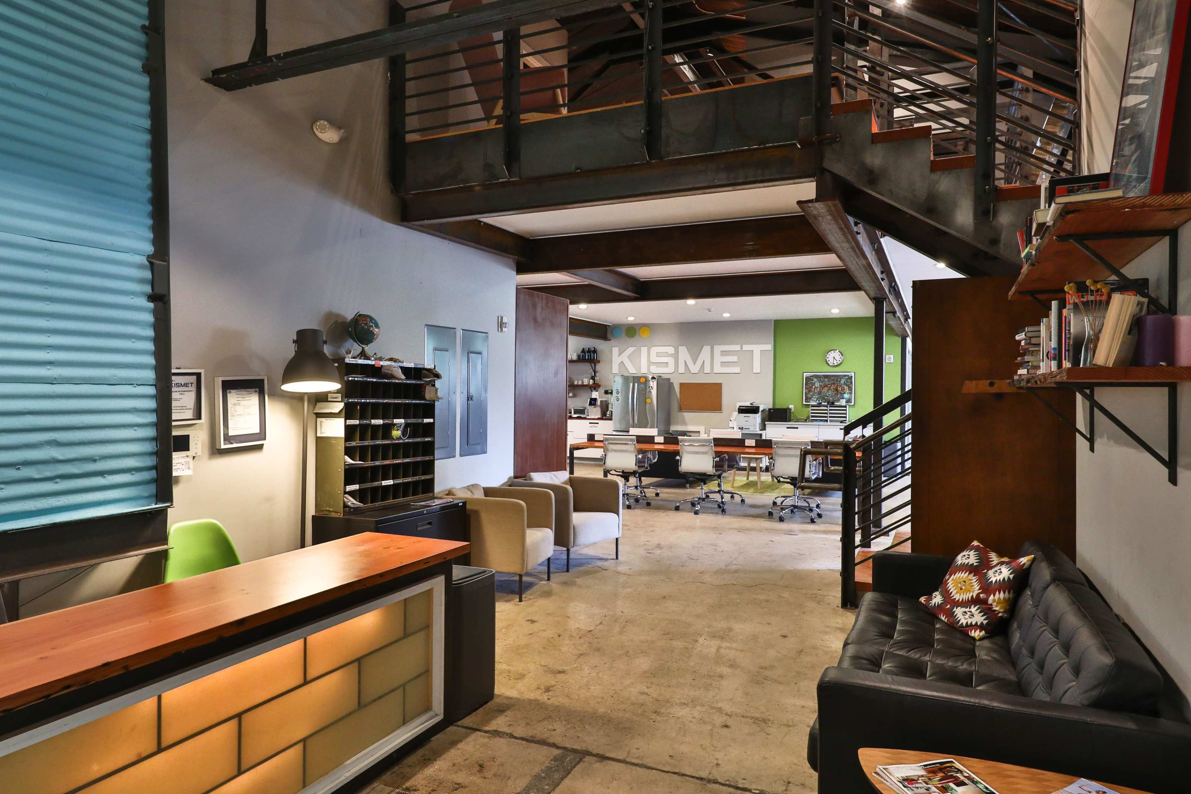 A modern office space with a reception area, seating, and workstations arranged in an open layout, featuring contemporary furnishings and decor.