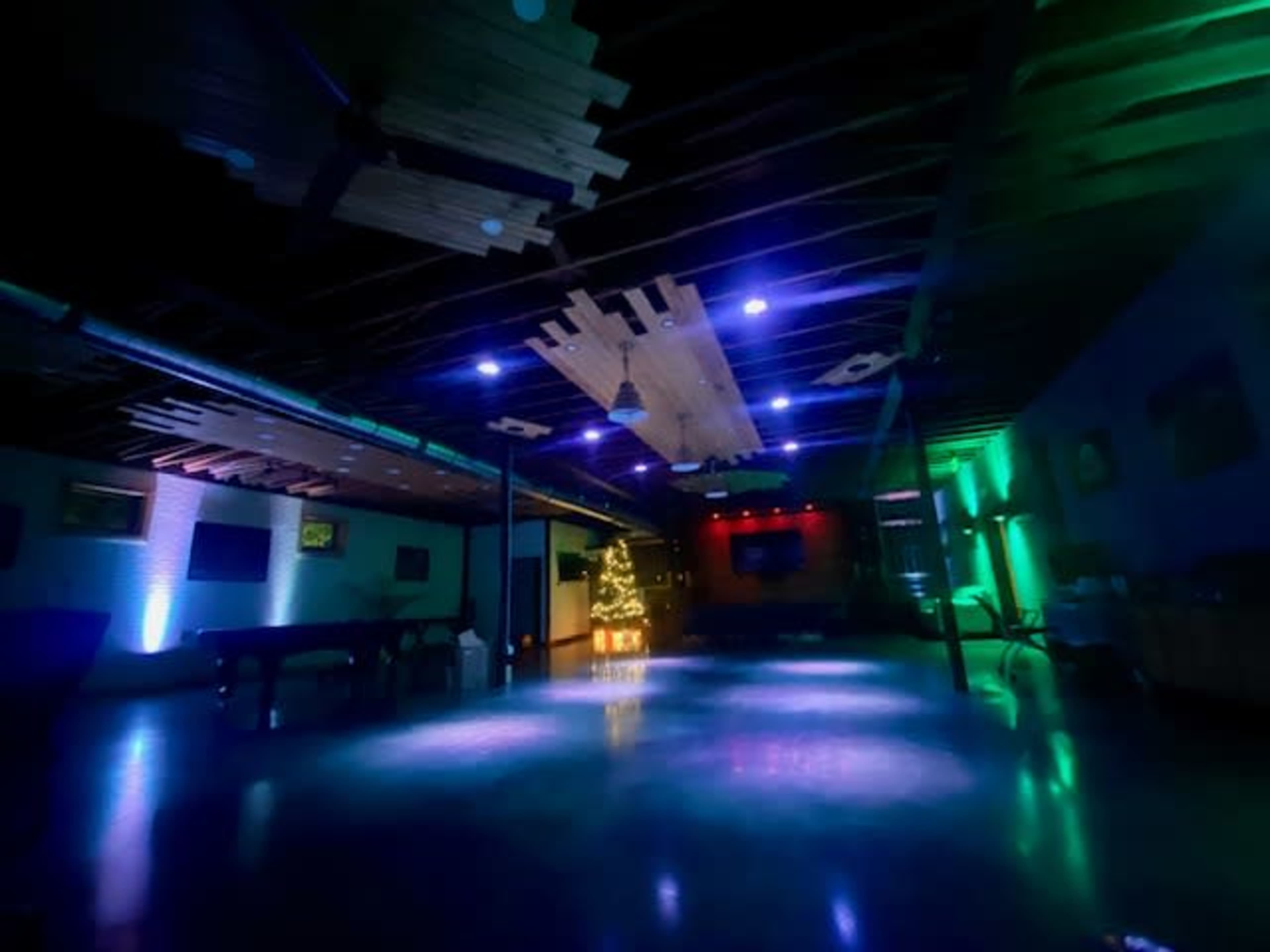 The image shows an empty dance floor illuminated by vibrant colored lights in a dimly lit indoor space.