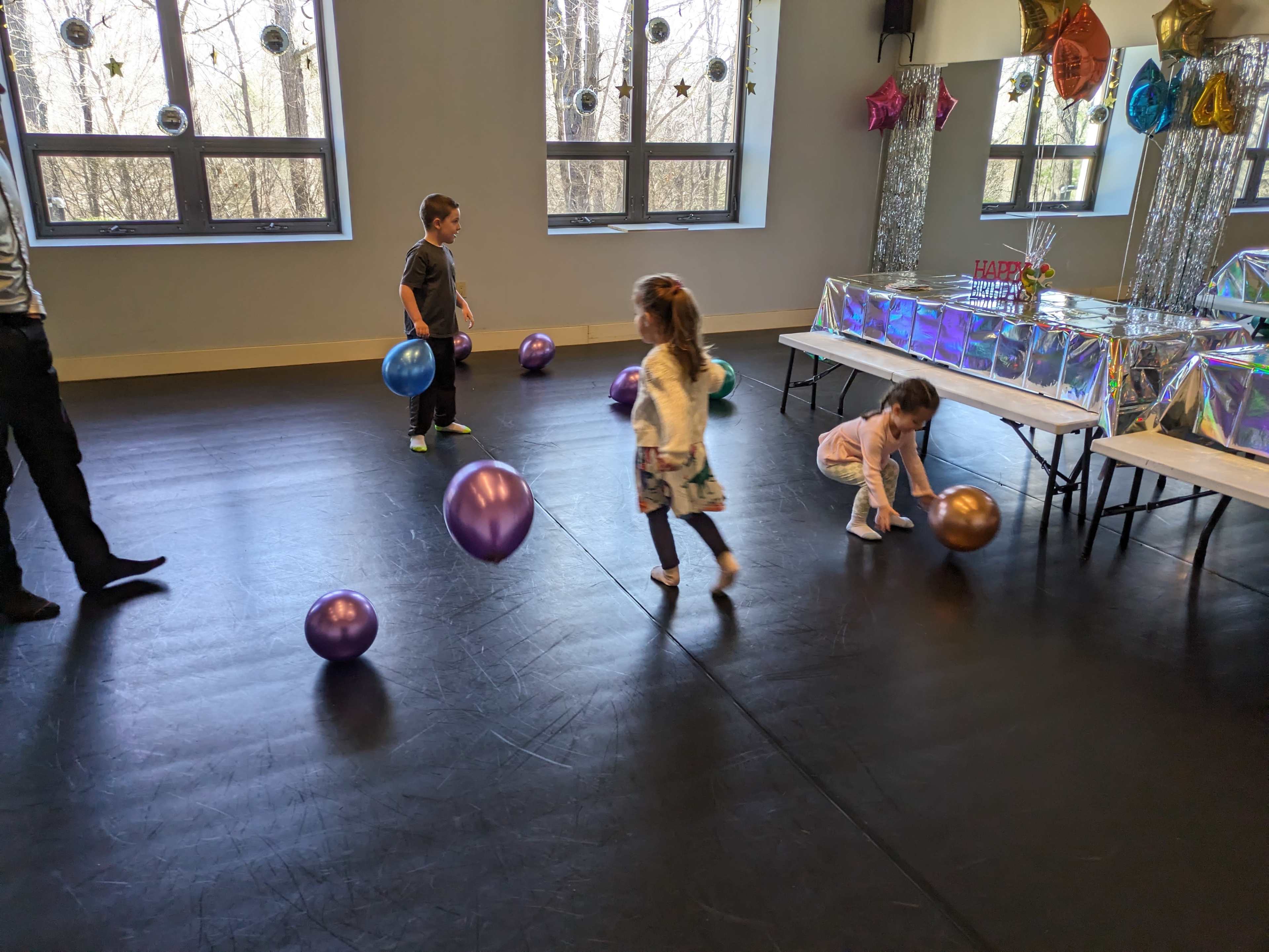 A group of children are playing with colorful balloons in a brightly lit room decorated for a celebration.