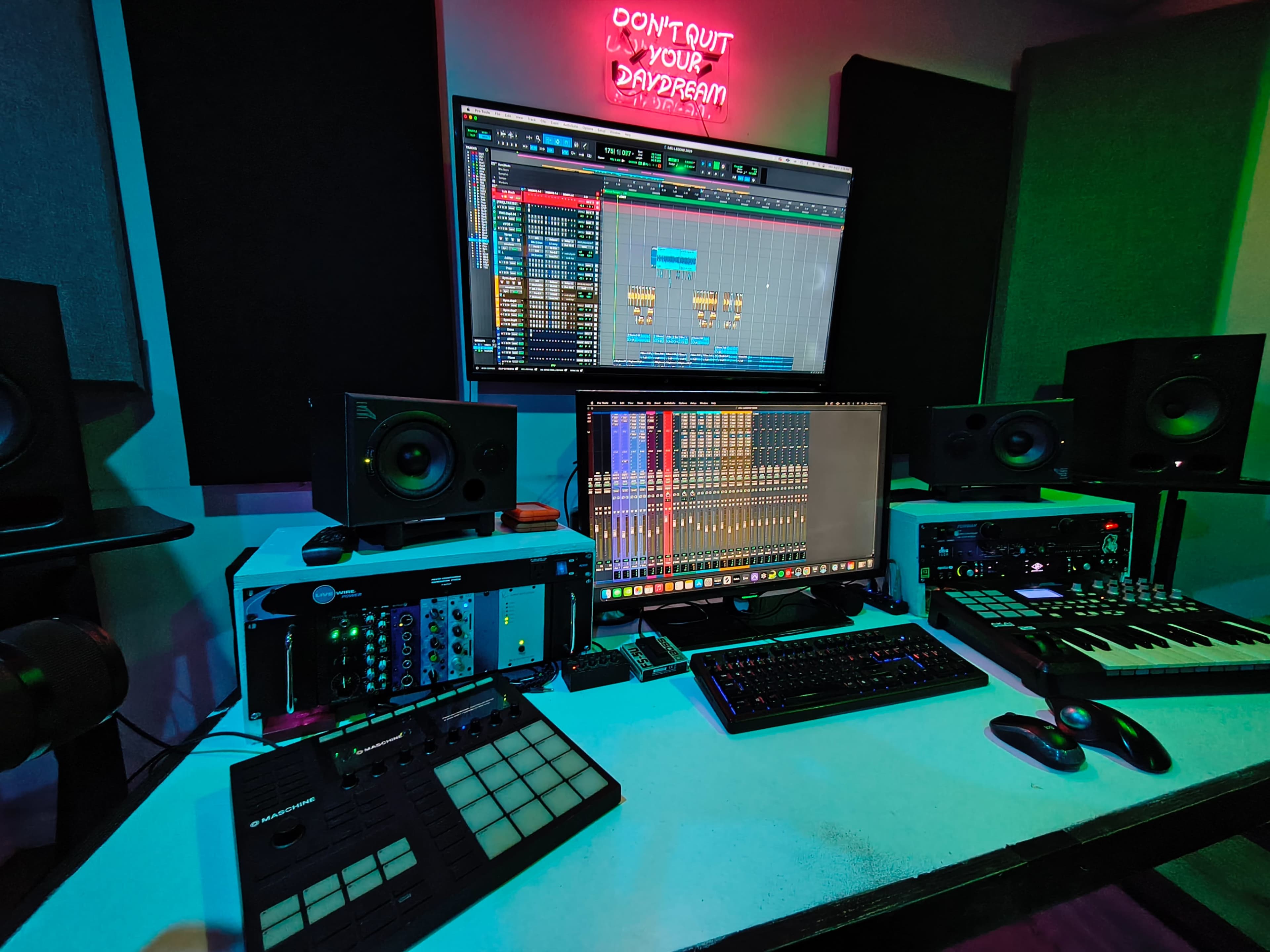 A modern music production studio features a computer setup with multiple monitors, audio interfaces, and a MIDI keyboard, surrounded by studio monitors.