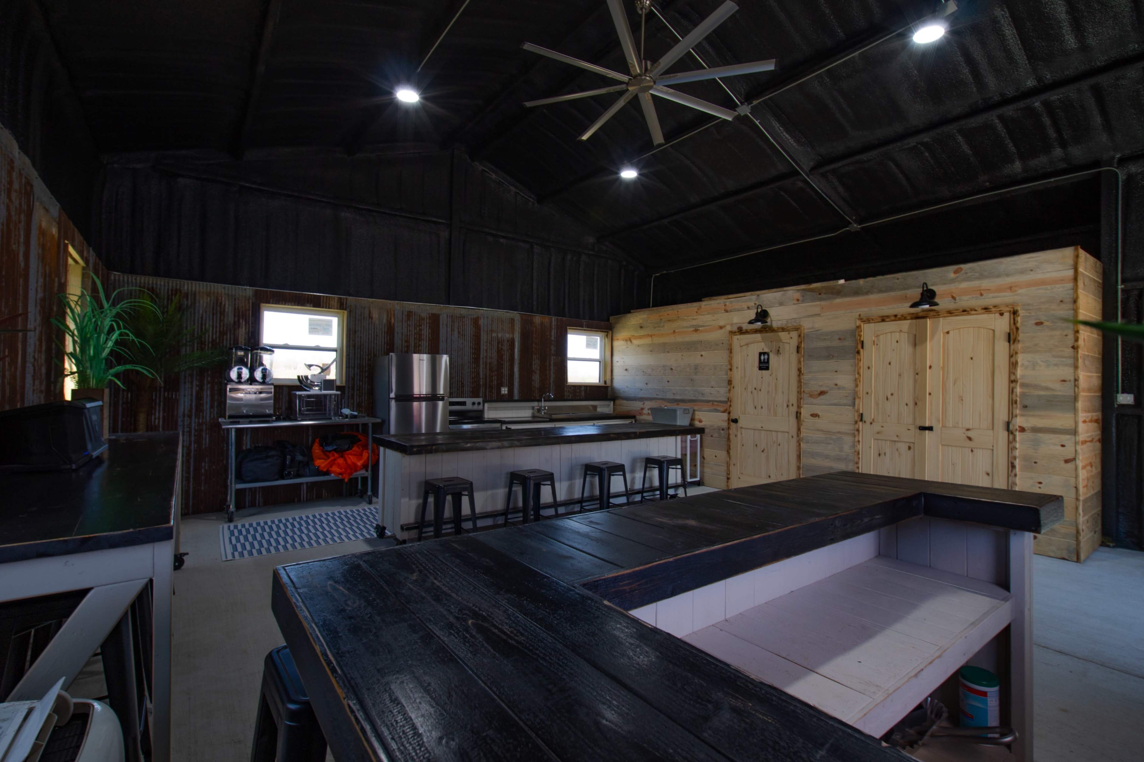 The image shows a spacious industrial-style kitchen with metal appliances, wooden accents, and a large central island with seating.