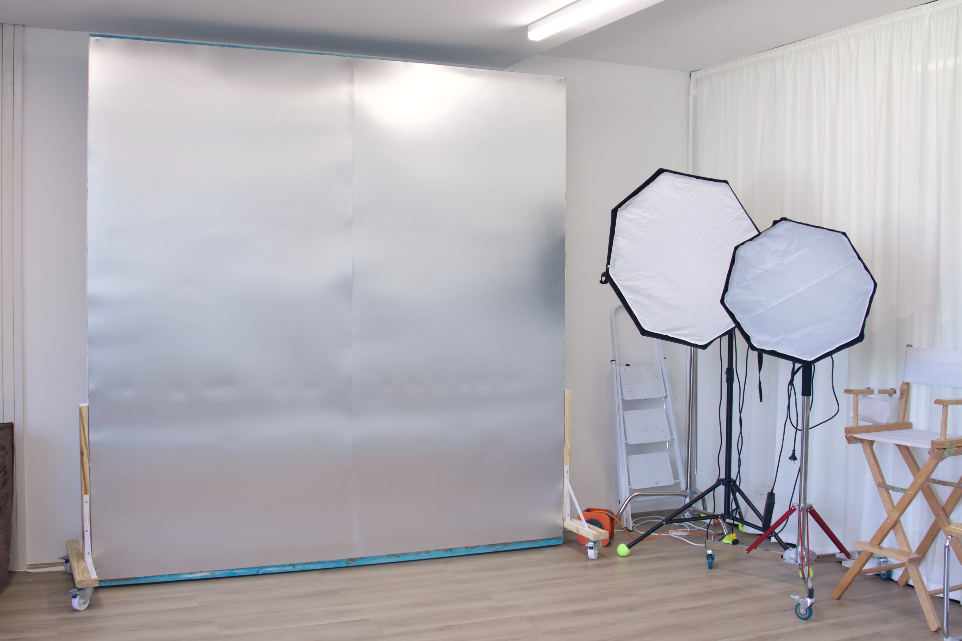 The scene shows a photography studio with a large silver backdrop and two softbox light sources.