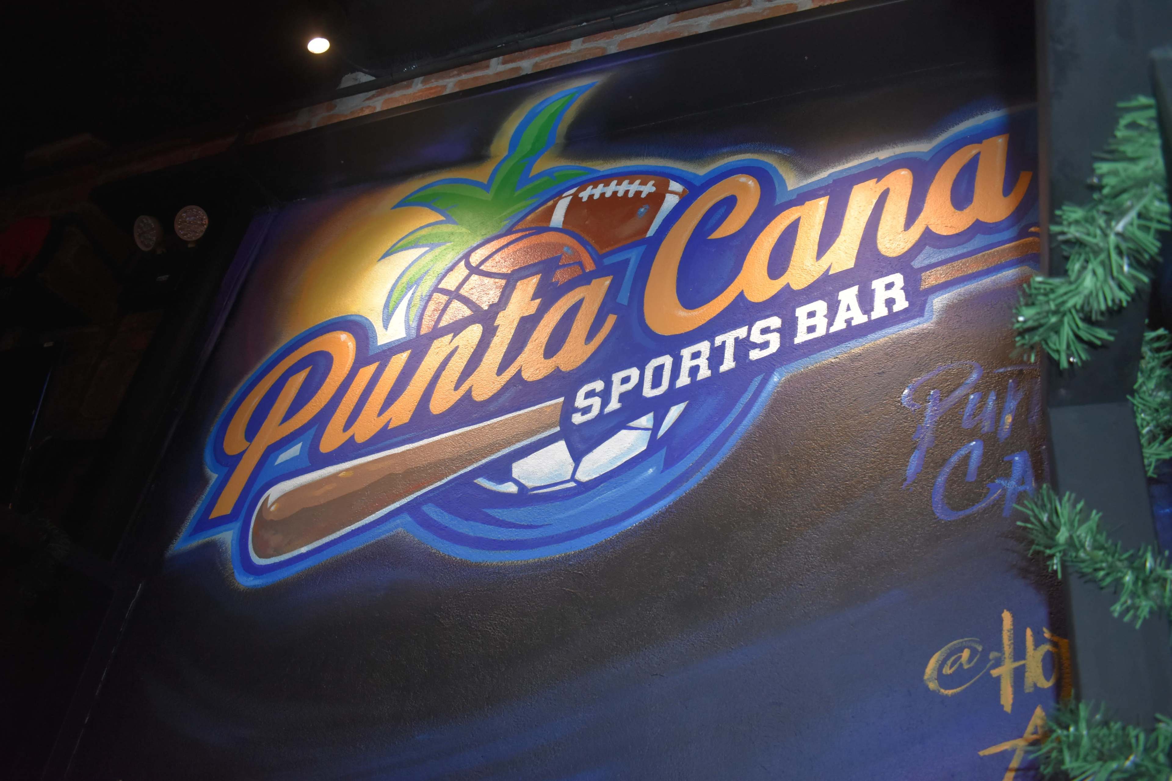 The image features a vibrant mural that displays the name "Punta Cana Sports Bar" along with various sports-related imagery, including a football and a baseball bat.