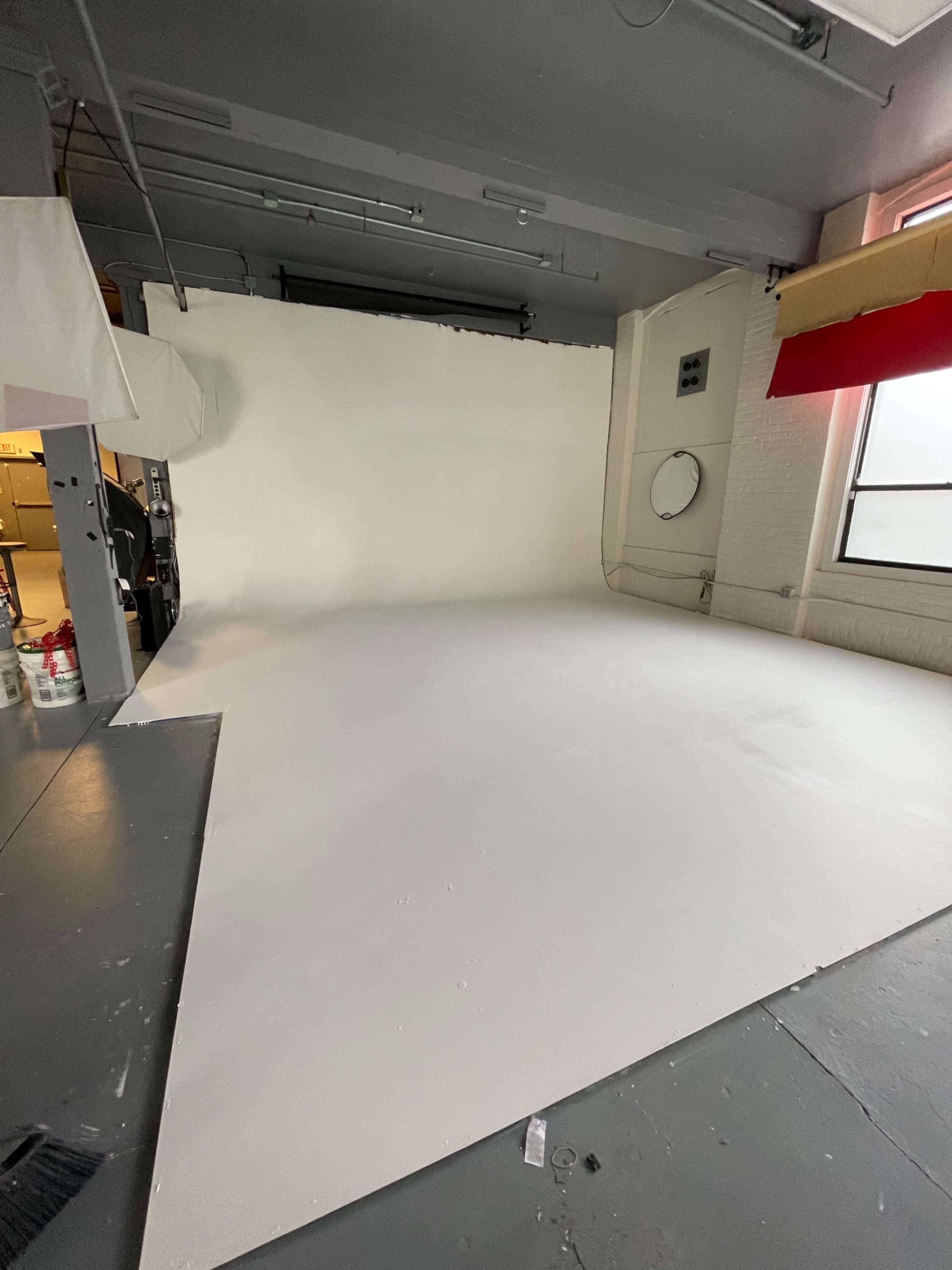 A spacious photography studio features a large white backdrop and a clean floor.
