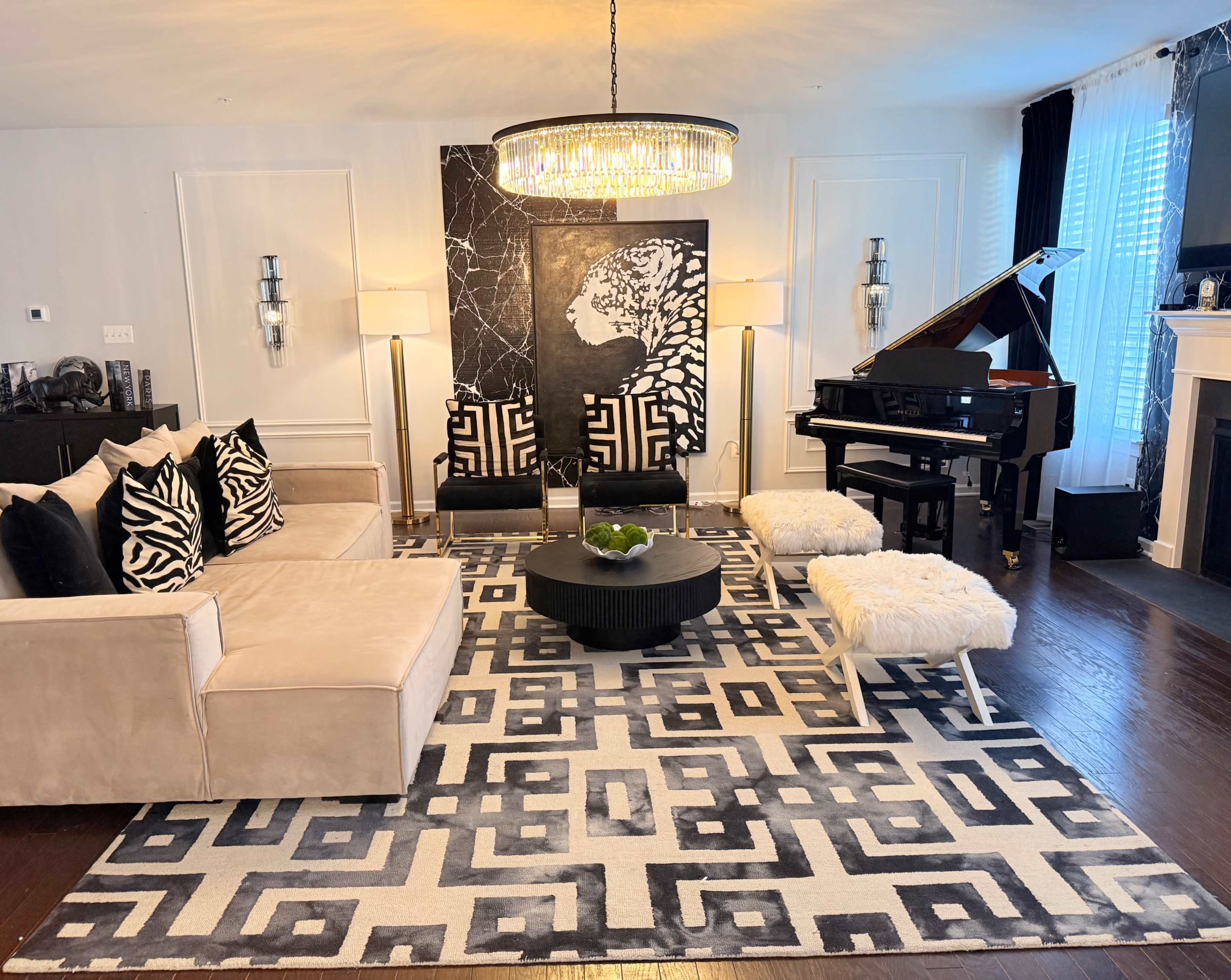 The living room features modern furnishings, a grand piano, and a large area rug with geometric patterns.