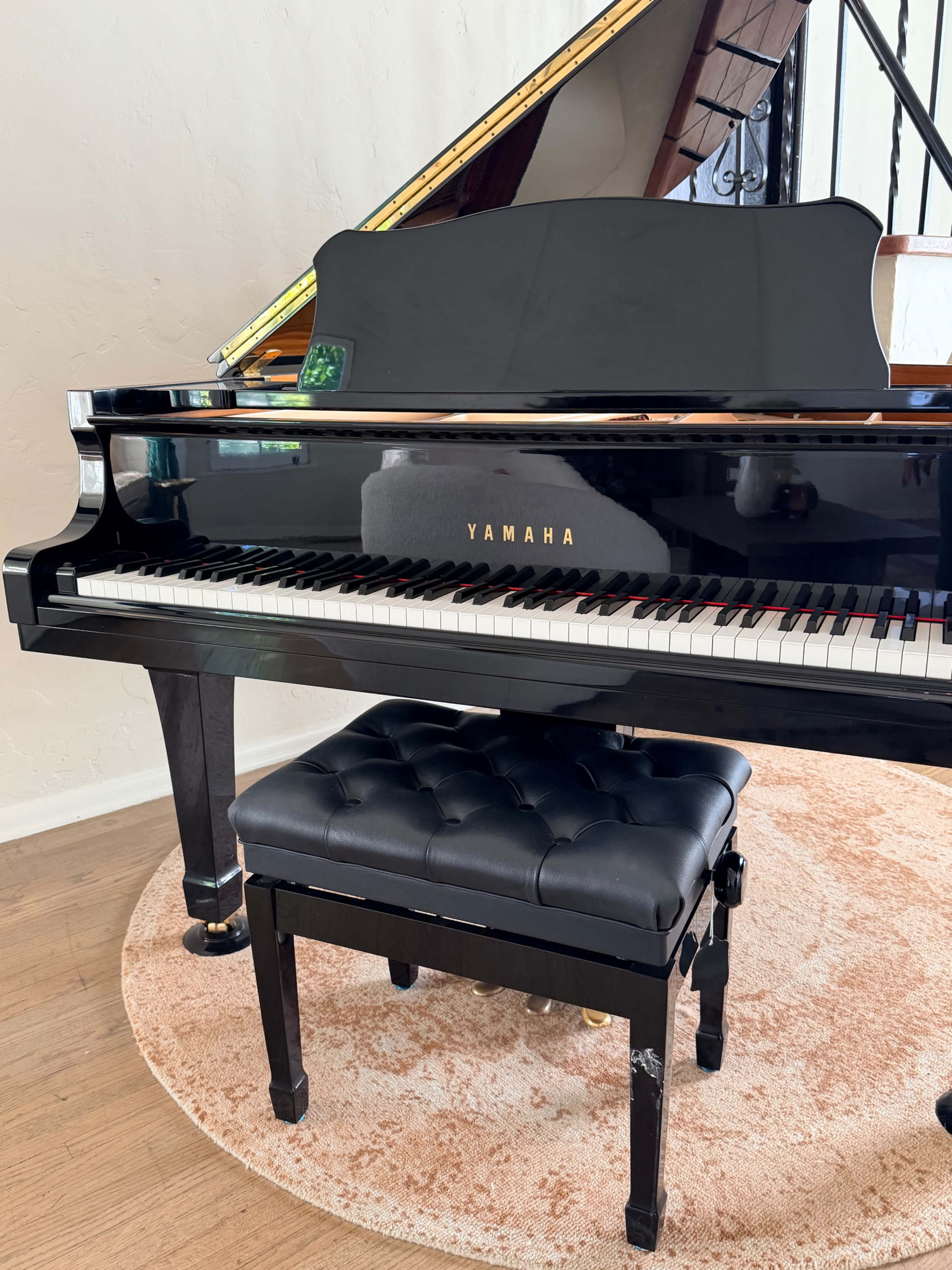 A Yamaha grand piano is positioned on a circular rug, accompanied by a black padded bench.