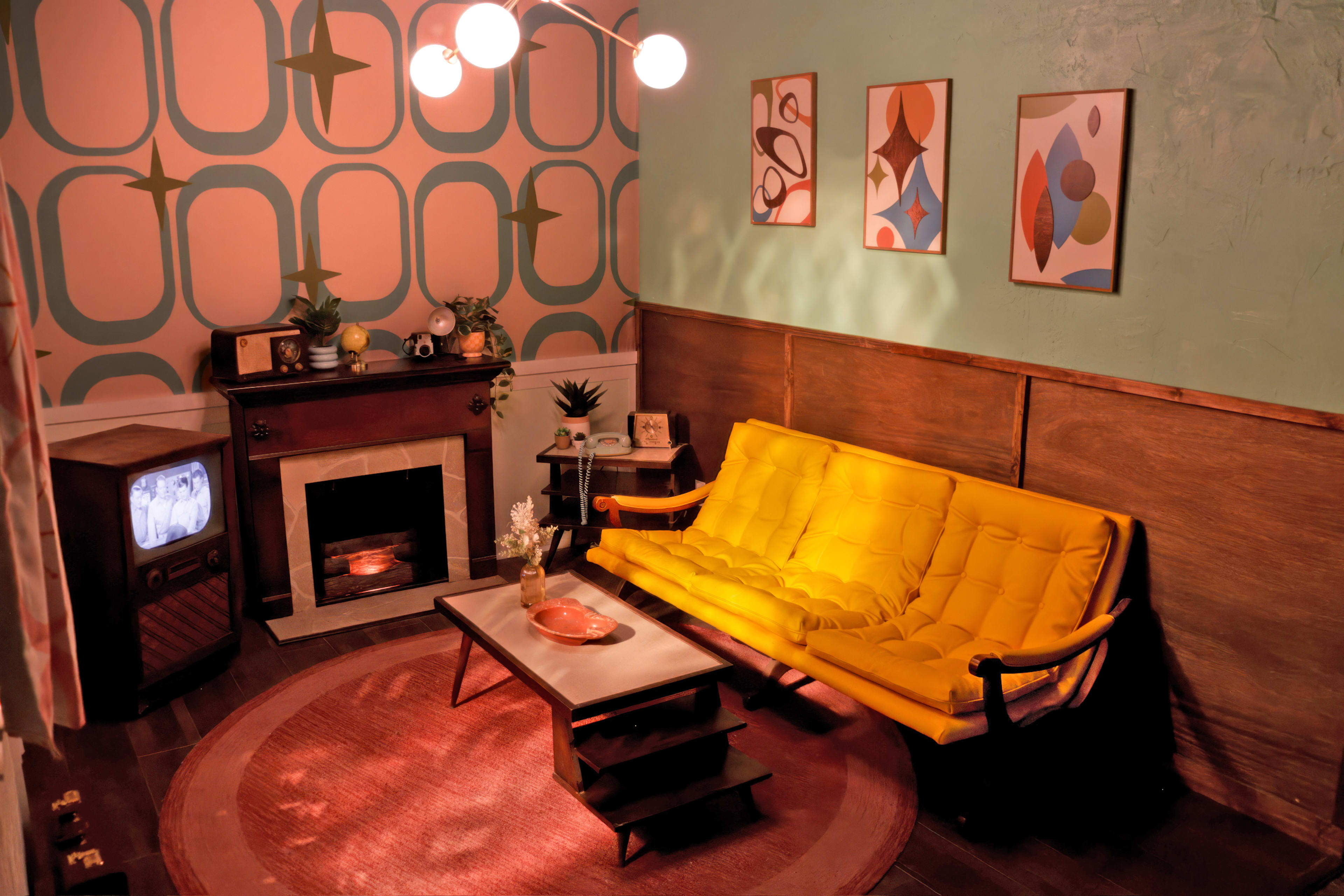 The image shows a retro-styled living room featuring a yellow sofa, a fireplace, a circular rug, and vintage wall art.