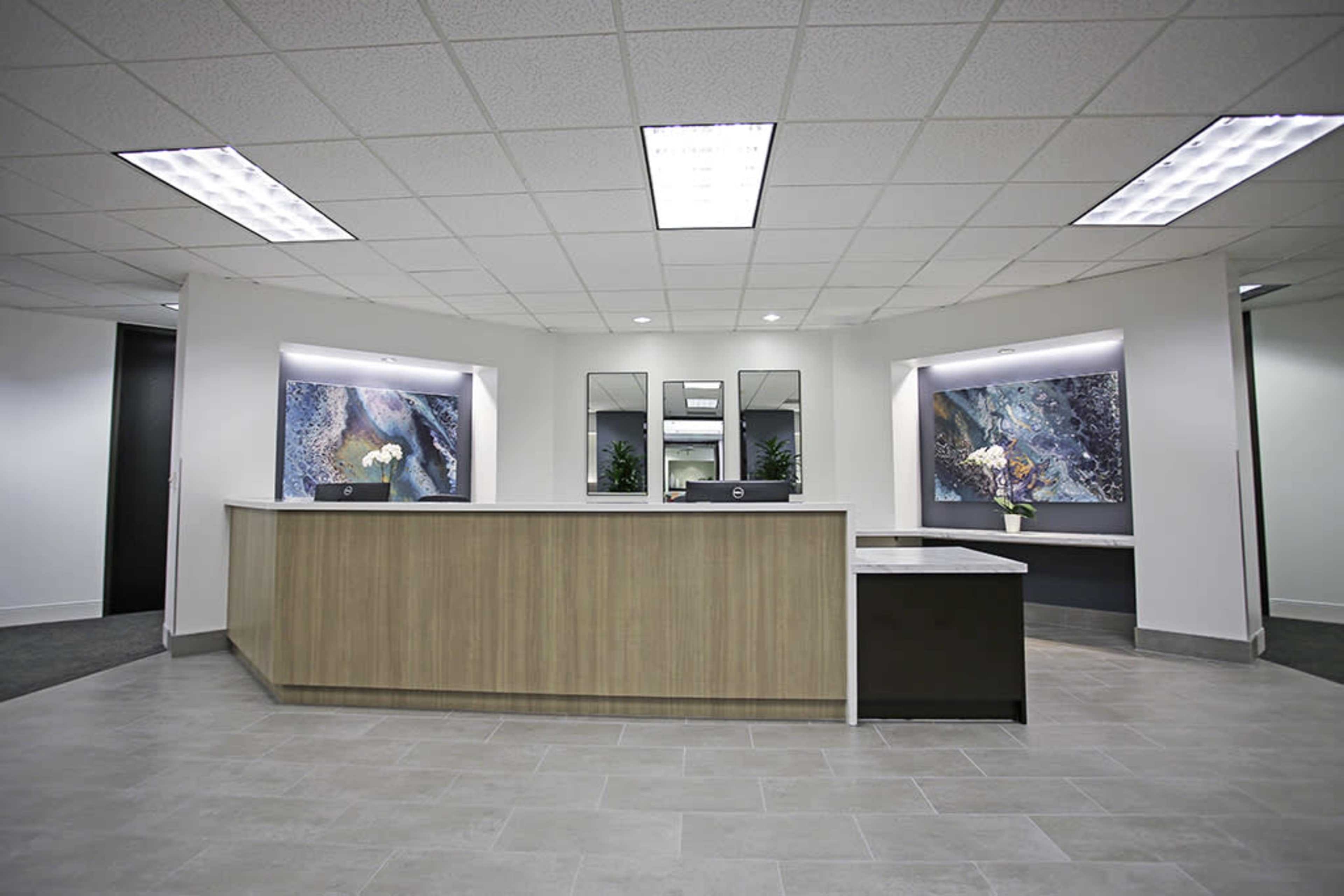 A modern reception area with a curved wooden front desk and abstract artwork on the walls.