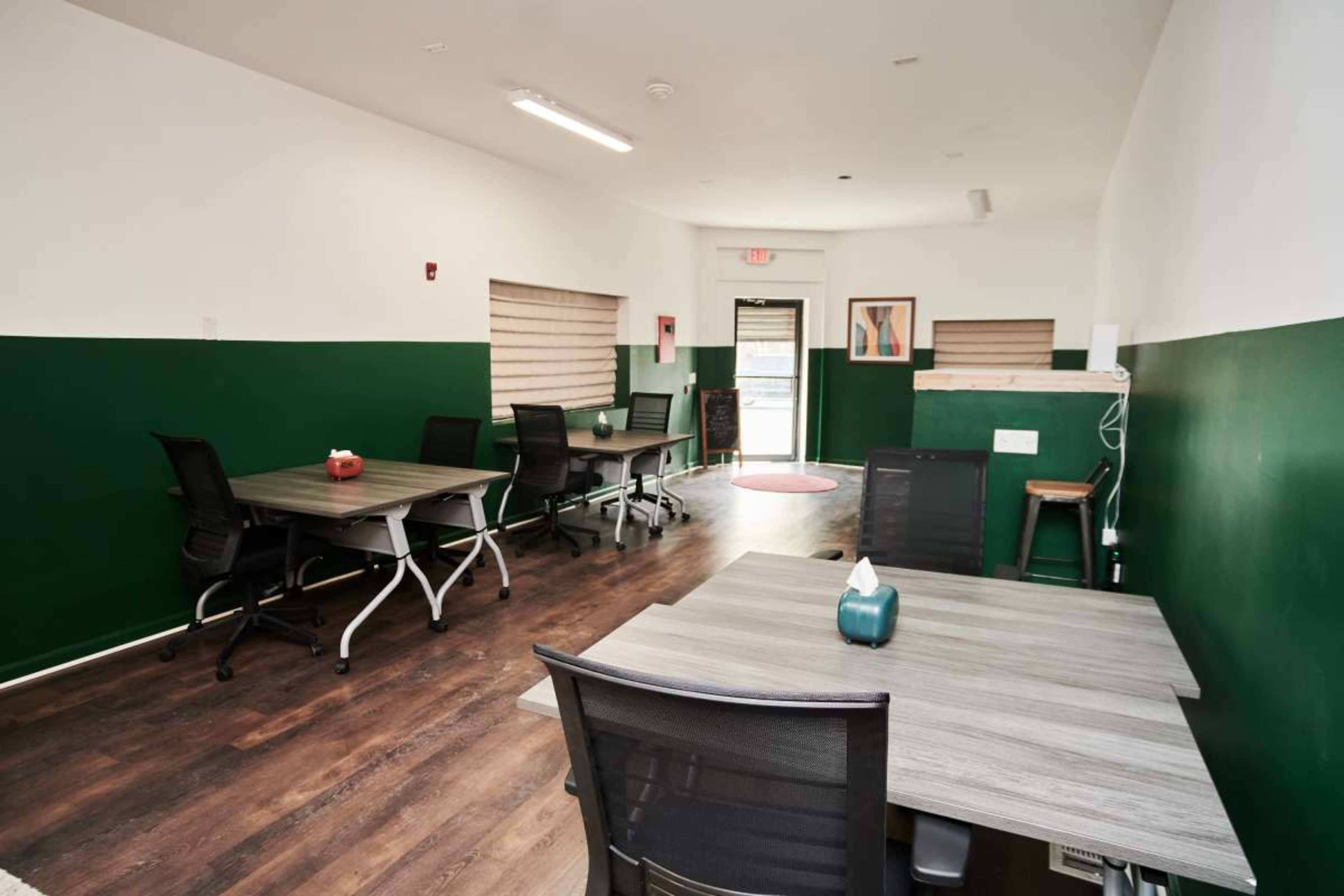 An office space featuring several desks arranged with a green and white color scheme.