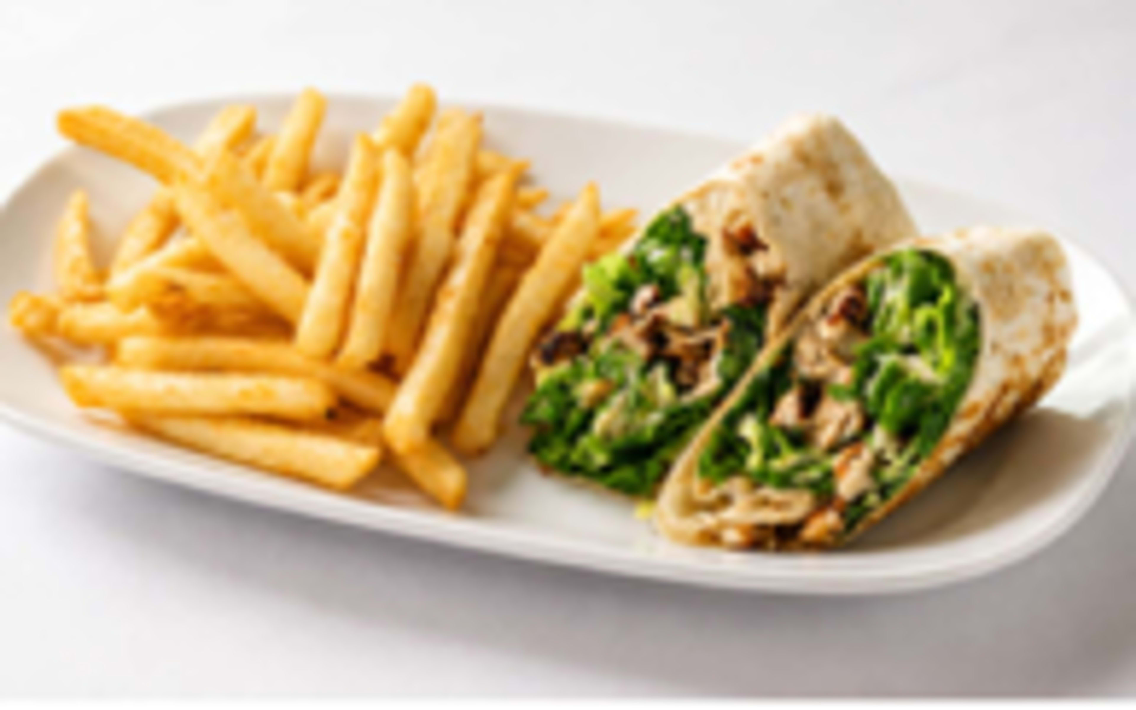 A plate features a sliced wrap filled with greens and chicken alongside a serving of golden French fries.