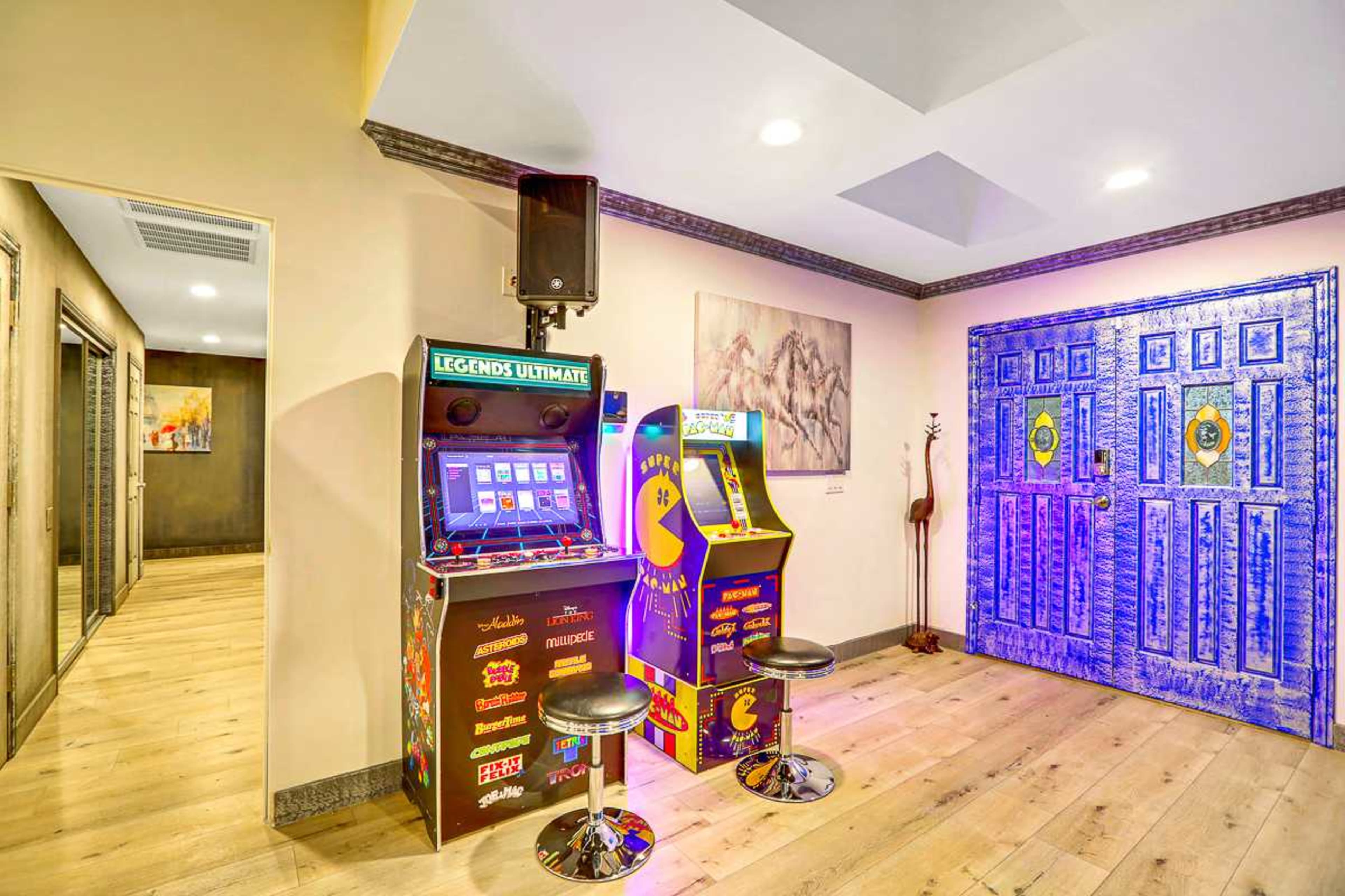 A gaming room featuring two arcade machines and a decorative blue door on the right.