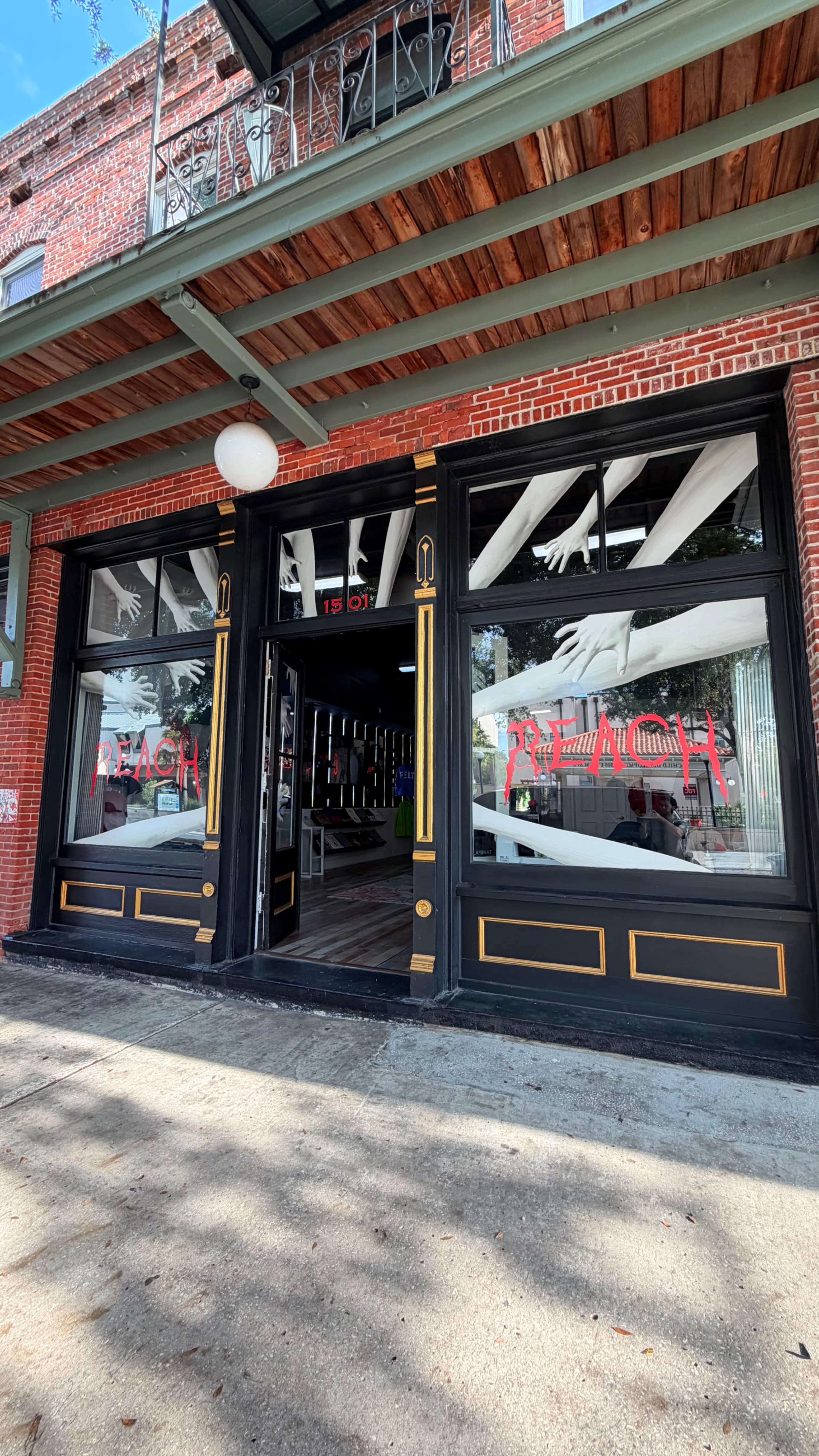 The image shows the entrance of a brick building with large windows displaying the word "REACH" in bold red letters.