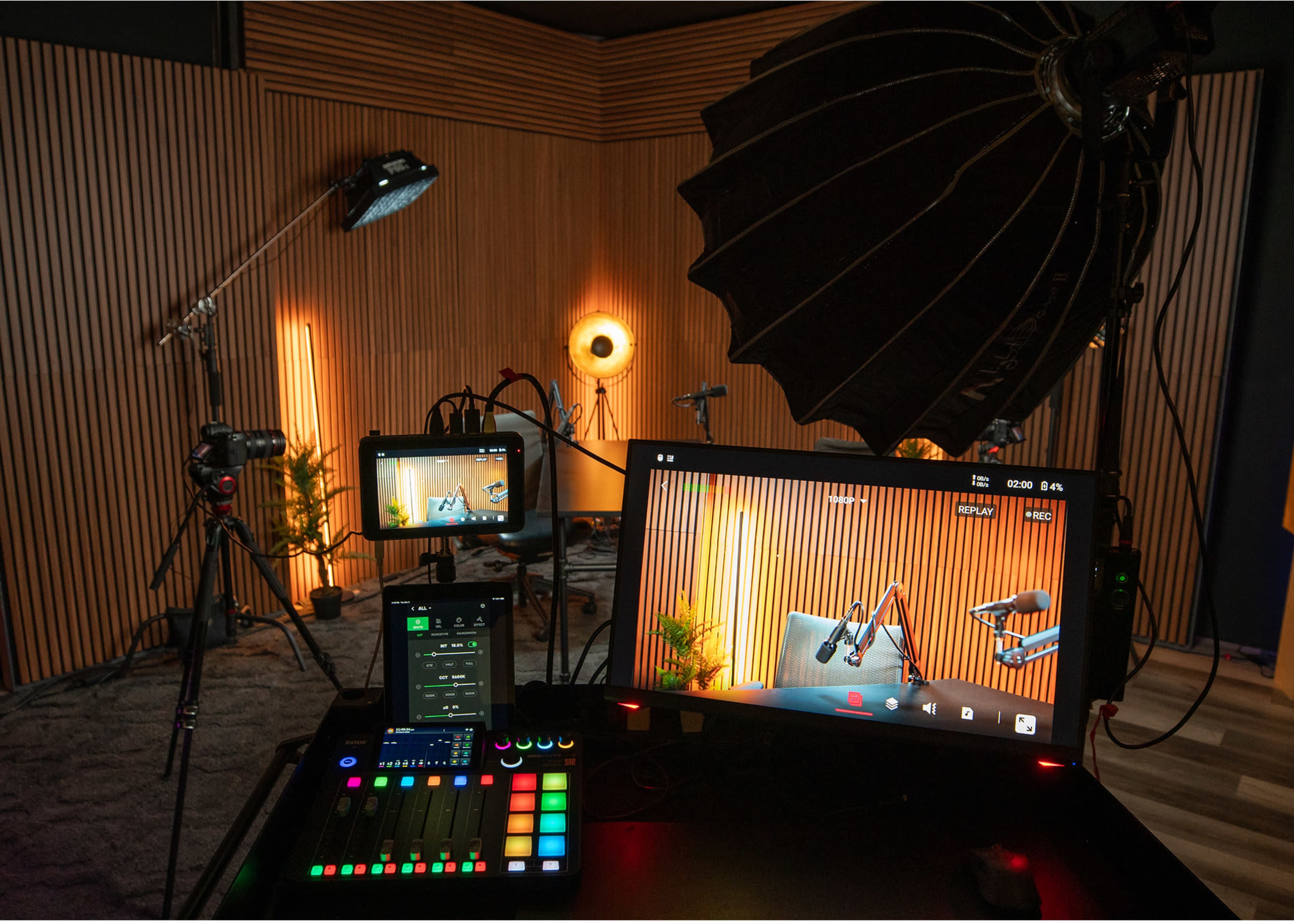 The image shows a well-equipped video recording studio with cameras, lighting, and screens set up against a wooden wall.