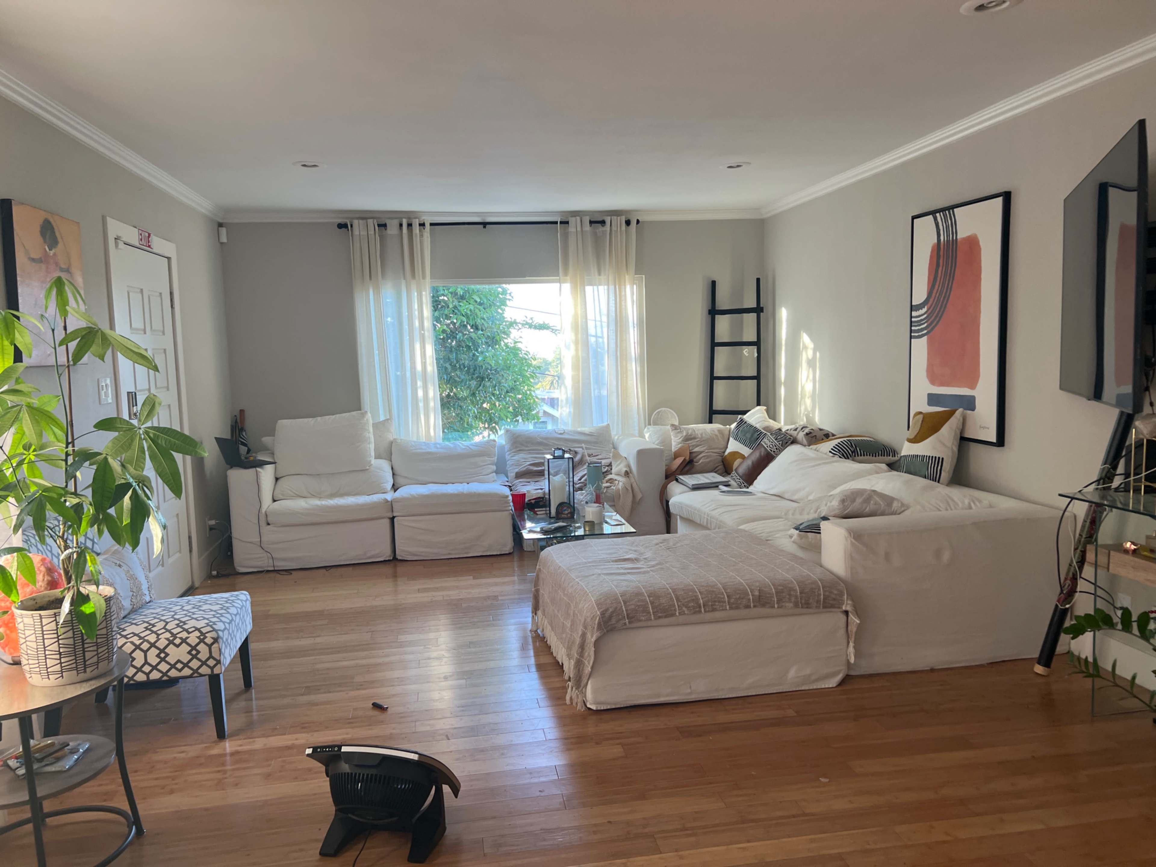 A living room with two white sofas, a coffee table, a decorative chair, and large windows letting in natural light.