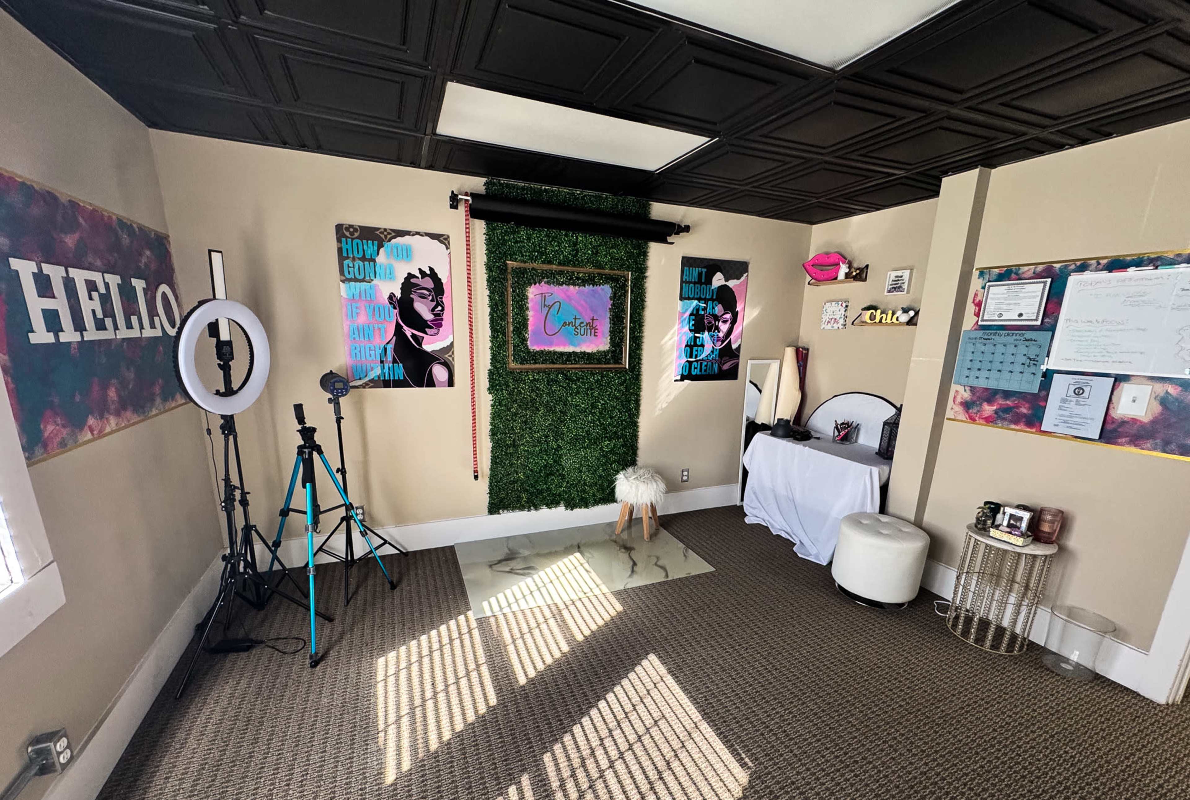 The image shows a creatively decorated interior room featuring a green moss wall, colorful wall art, and various props for photoshoots.