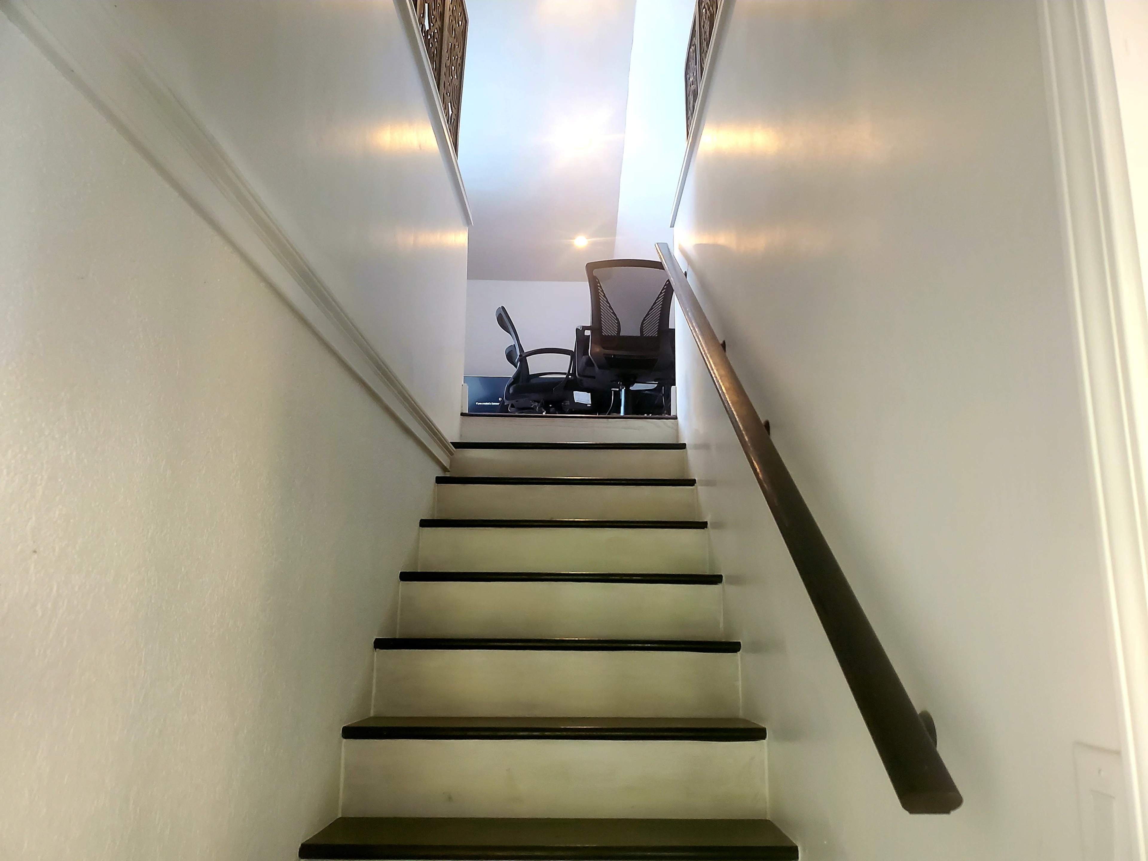 A stairway leads upward to a space with a chair and desk visible at the top.