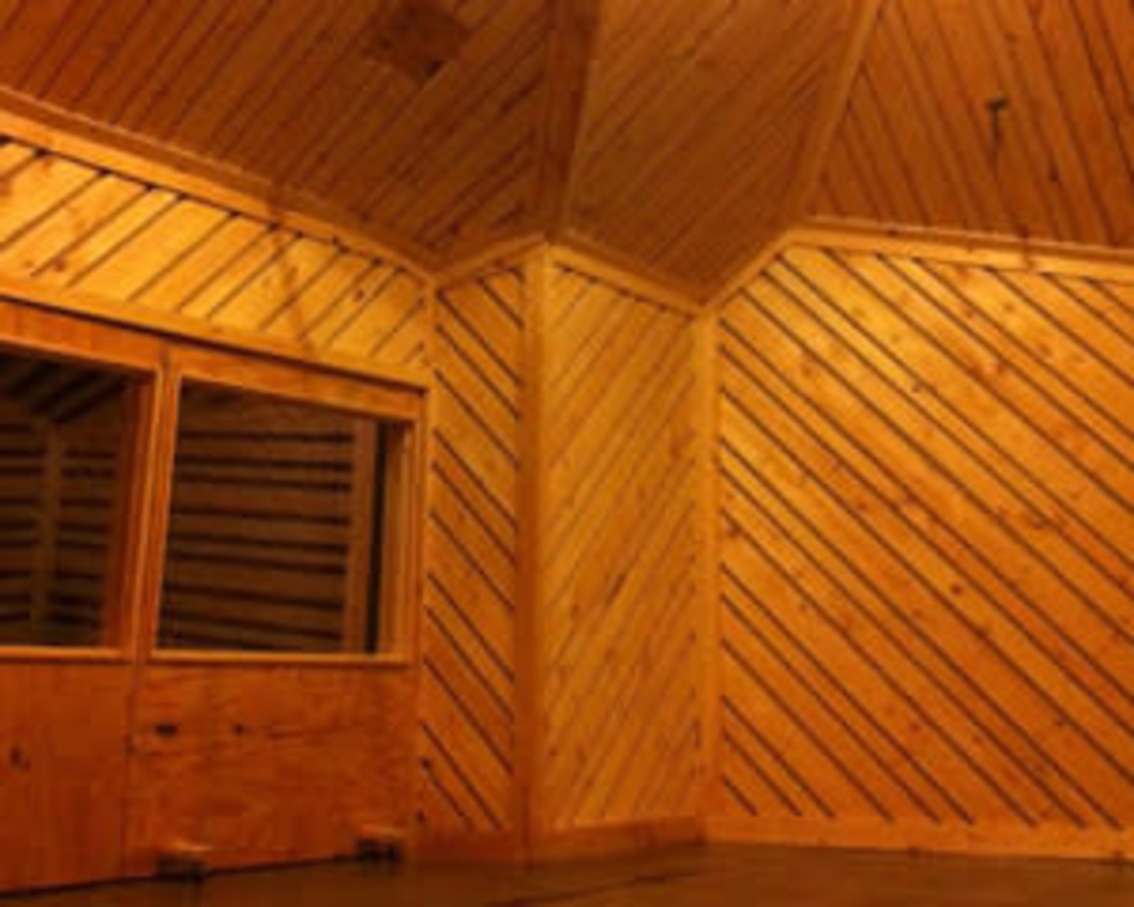 The image shows a wood-paneled room with diagonal wooden slats on the walls and a large window in one corner.
