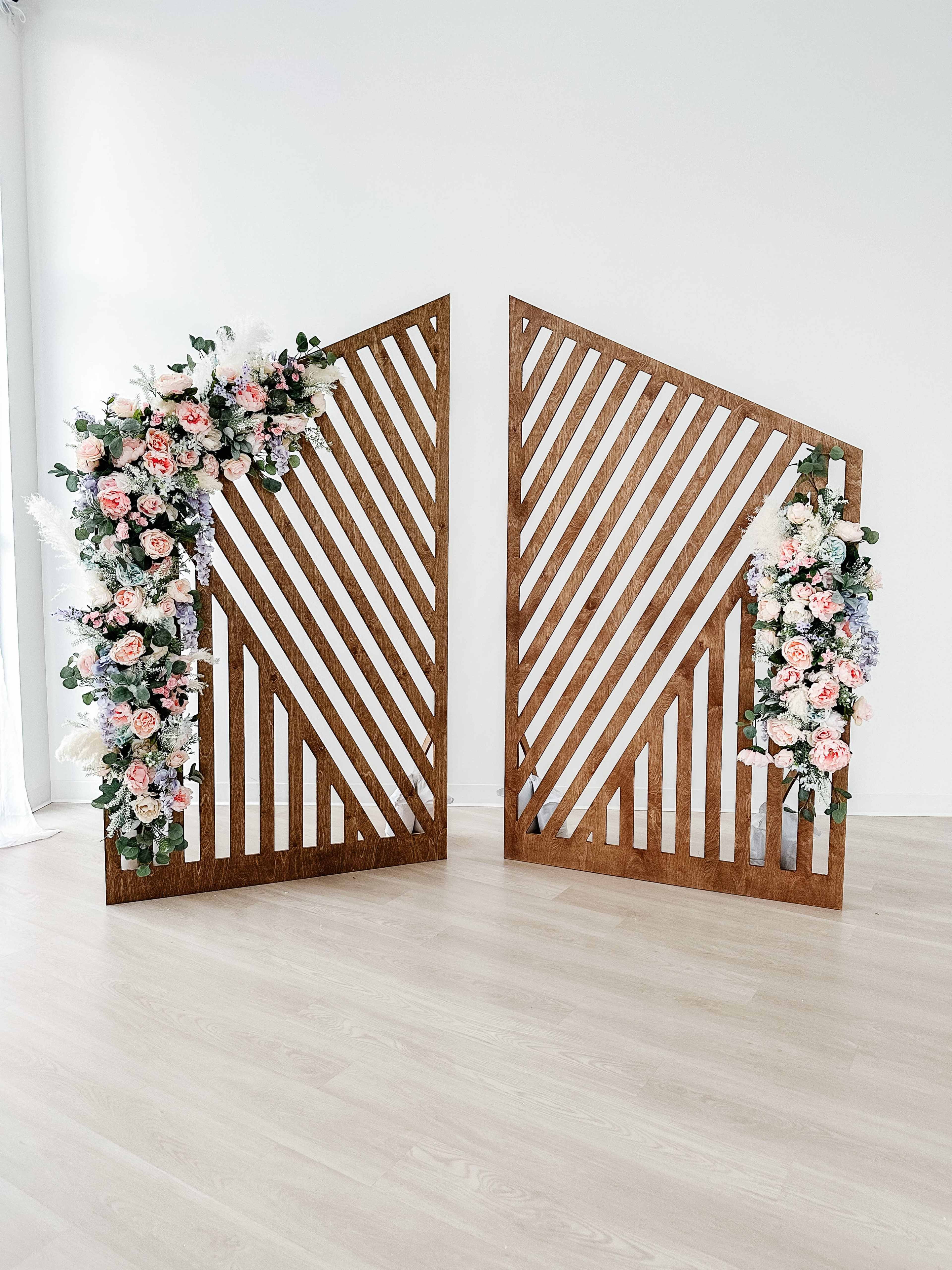 Two wooden panels with diagonal stripes, adorned with an arrangement of flowers and greenery on one side.