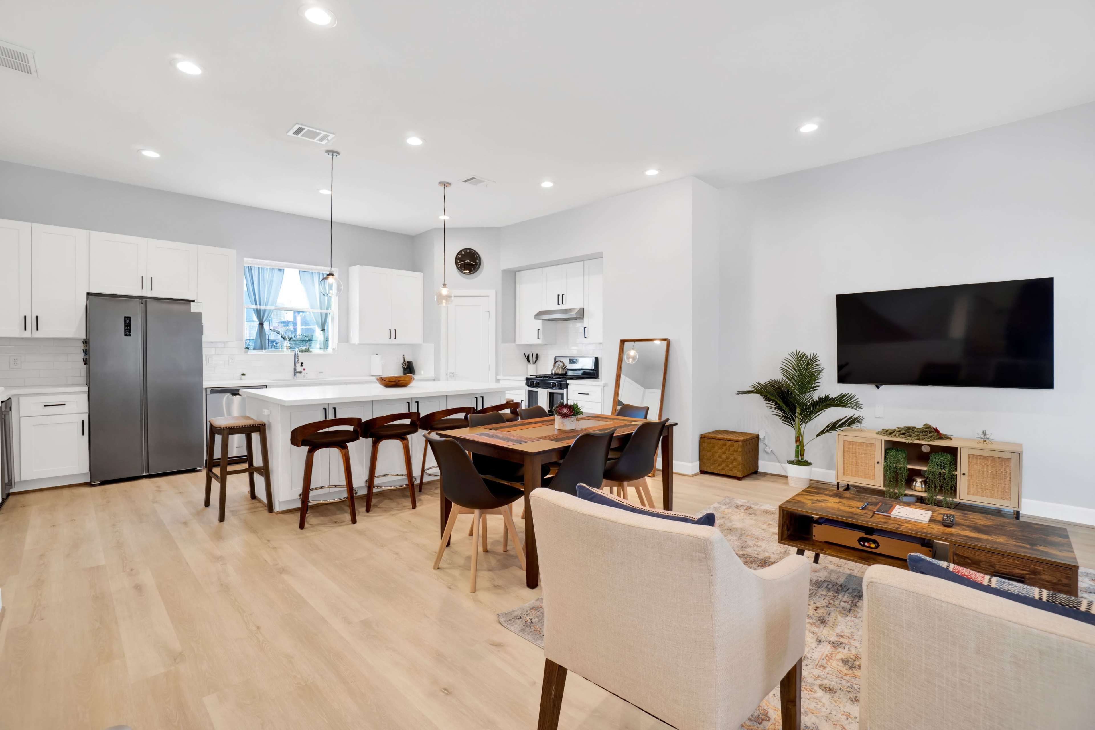 A modern open-concept kitchen and dining area with a sleek island, wooden dining table, and comfortable seating arrangement.