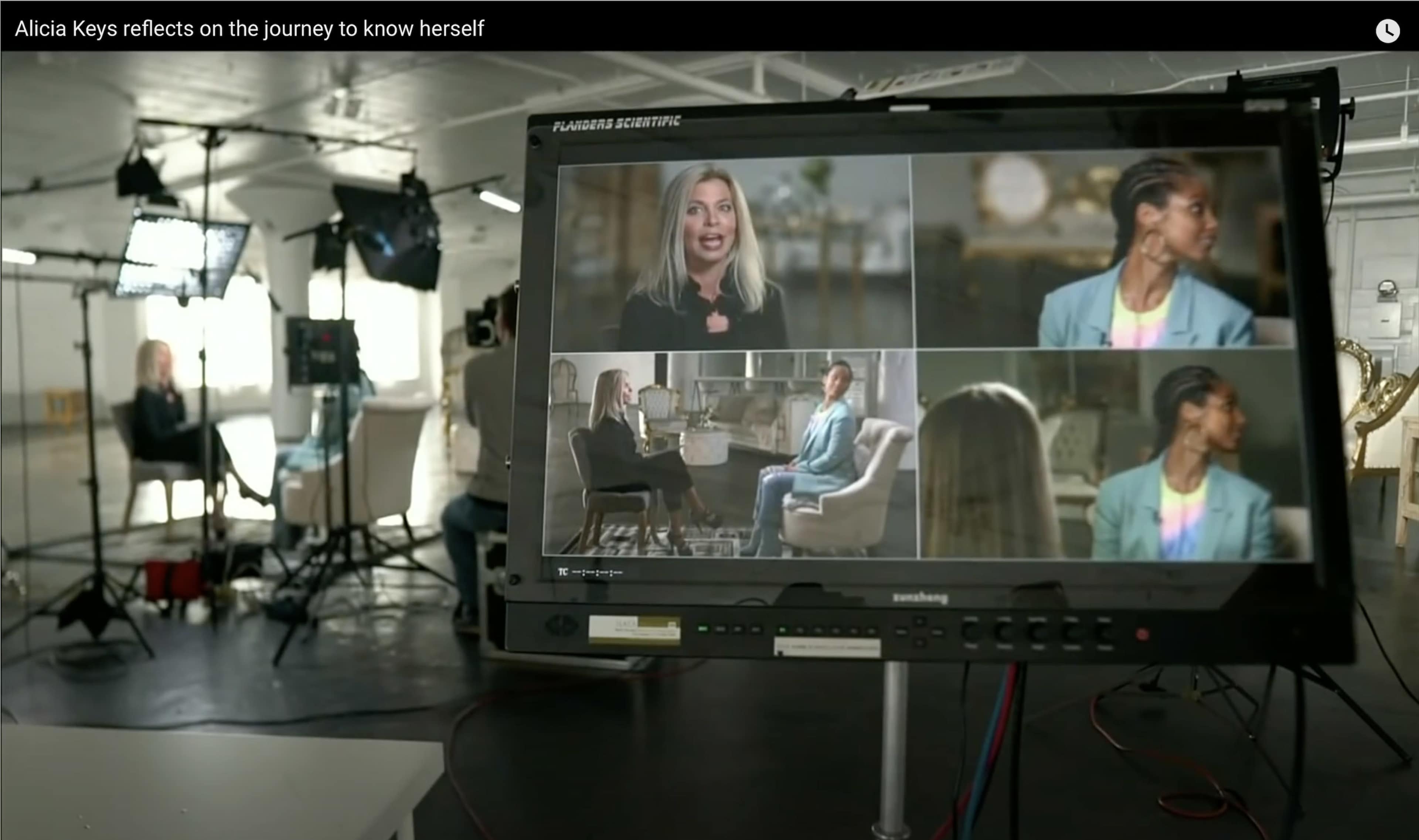 A television monitor displays multiple video frames of Alicia Keys during an interview in a studio setting.