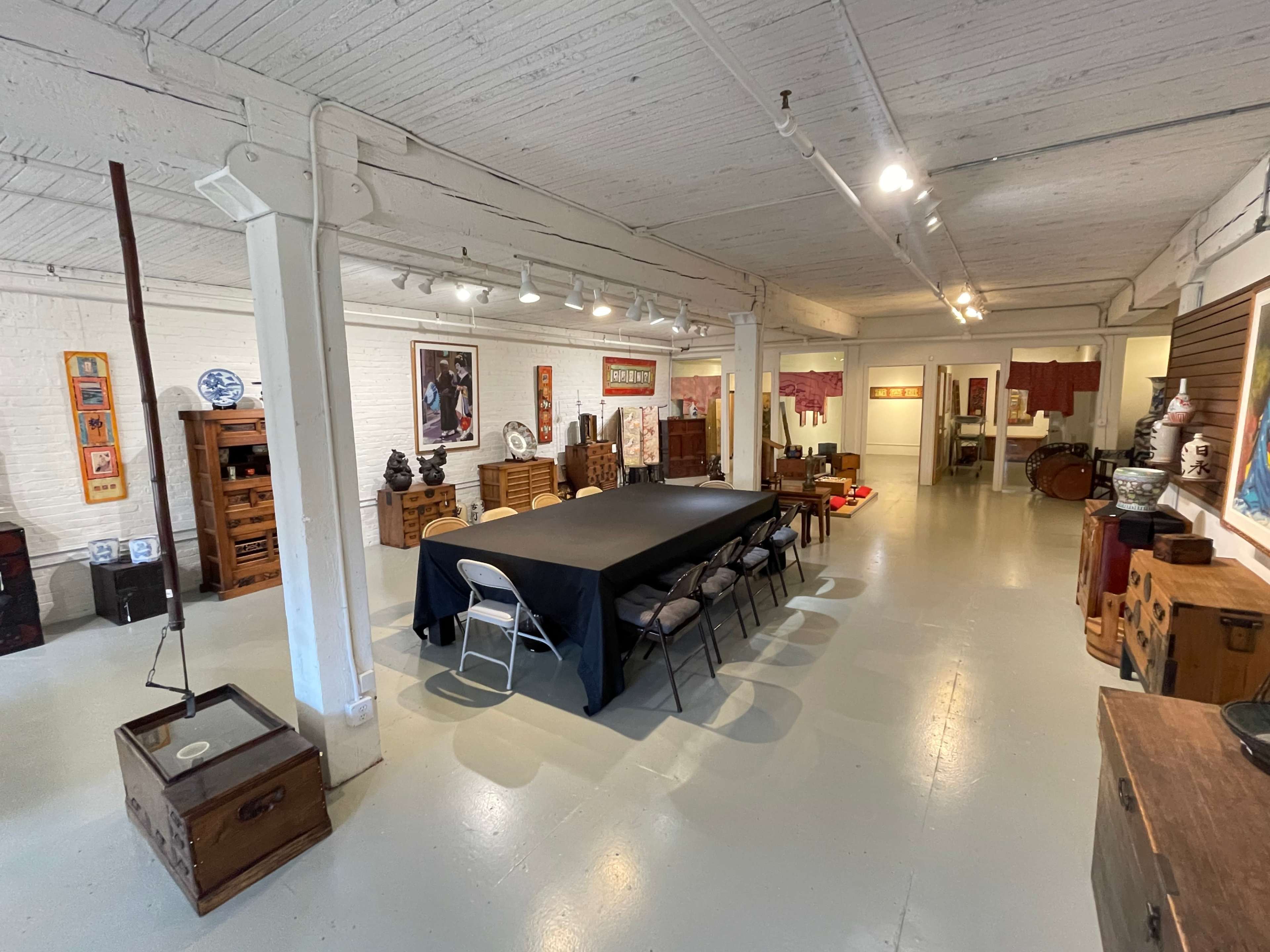 A spacious room with a long table surrounded by chairs, flanked by wooden furniture and decor on the walls.