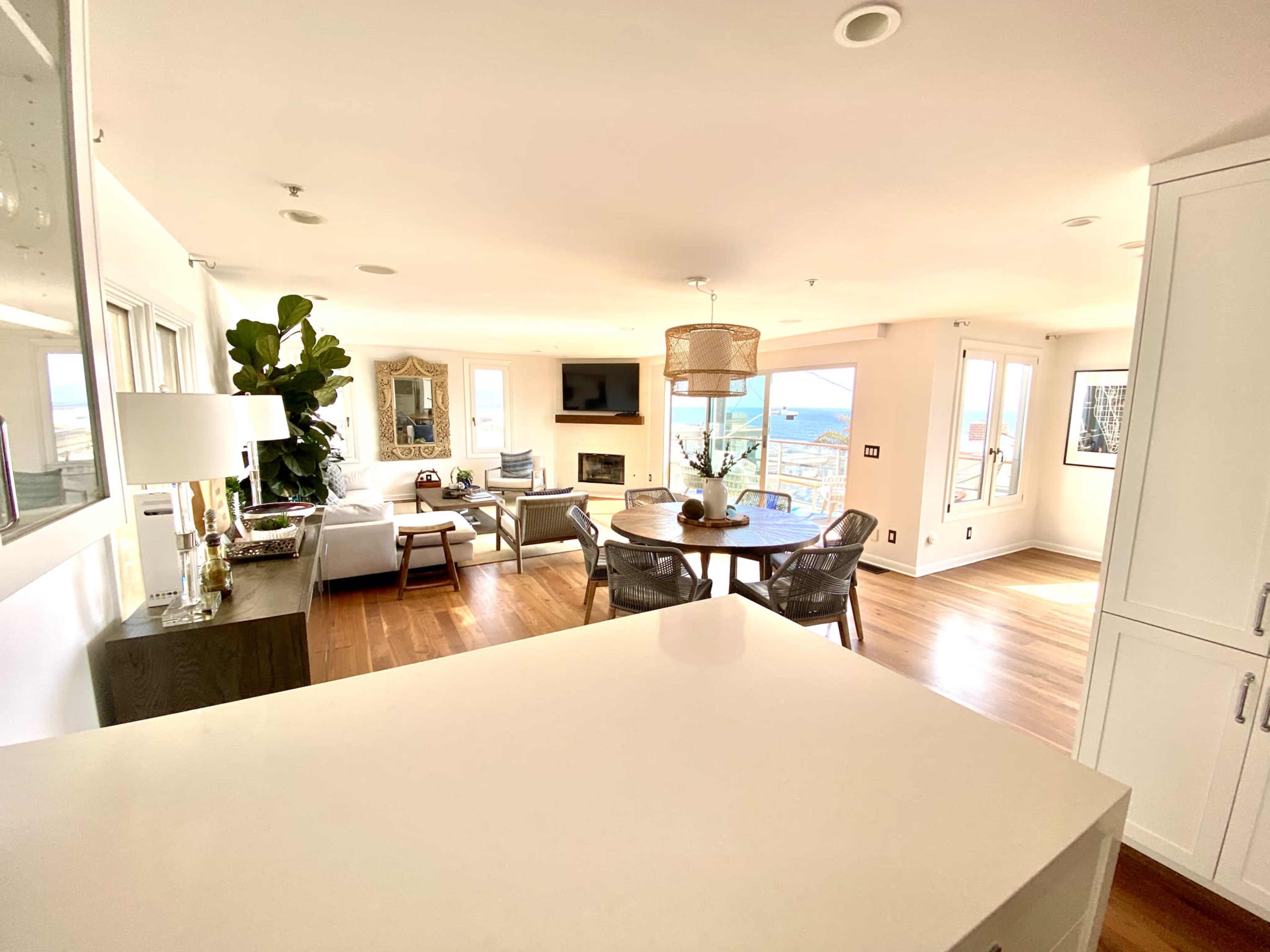 A bright, open-concept living area with a dining table, comfortable seating, and large windows overlooking a scenic view.