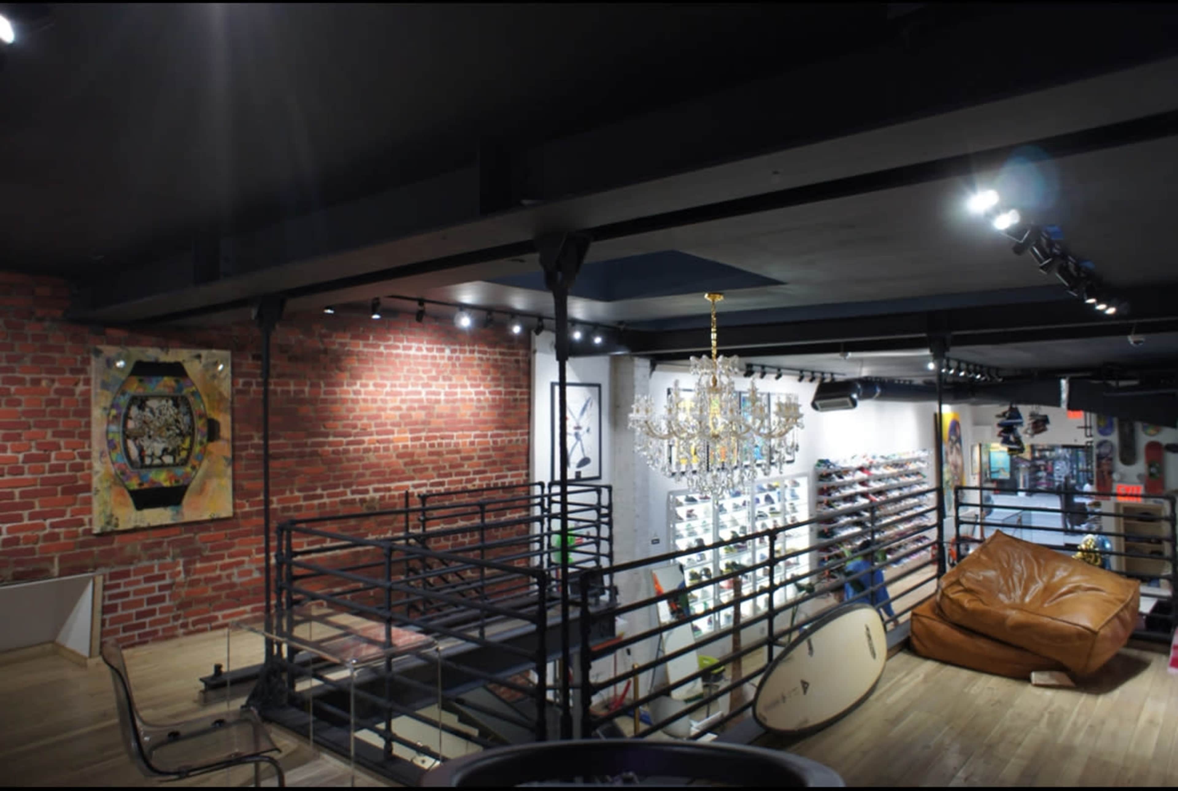 A spacious, modern retail interior with a brick wall, a chandelier, a large bean bag, and various displayed items on racks.