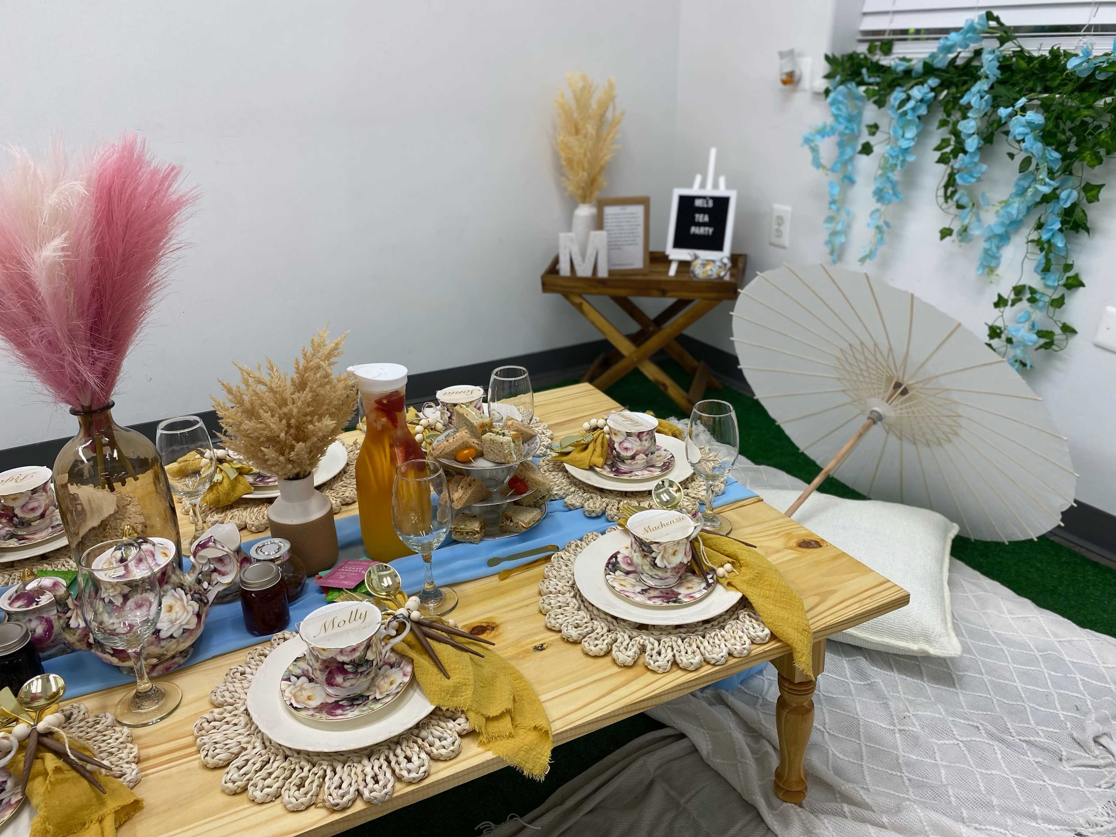 A table set for an elegant meal with floral-patterned dishes, glasses, and decorative elements, placed in a cozy, styled indoor space.