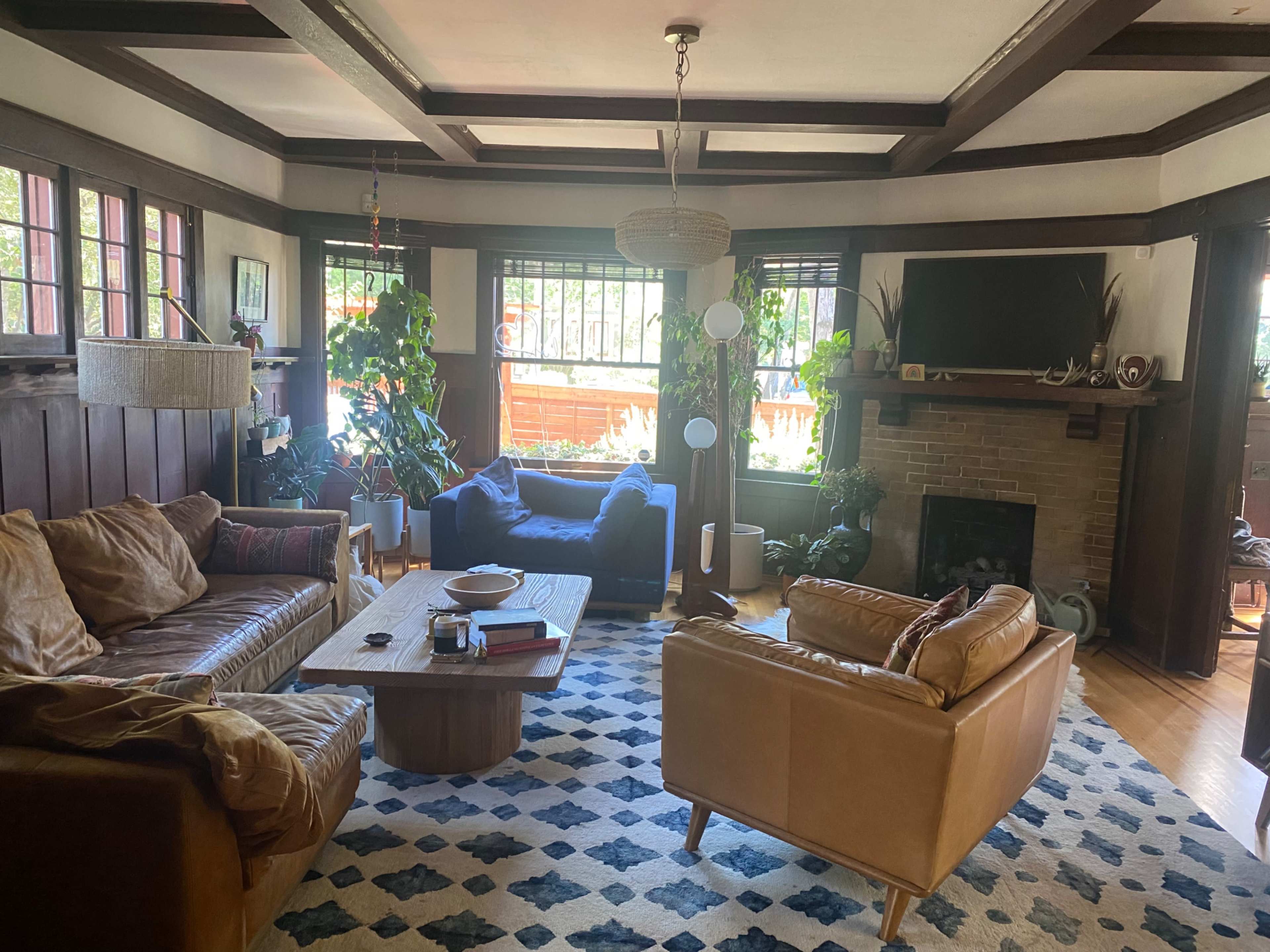A cozy living room with leather sofas, a coffee table, plants, and a fireplace.