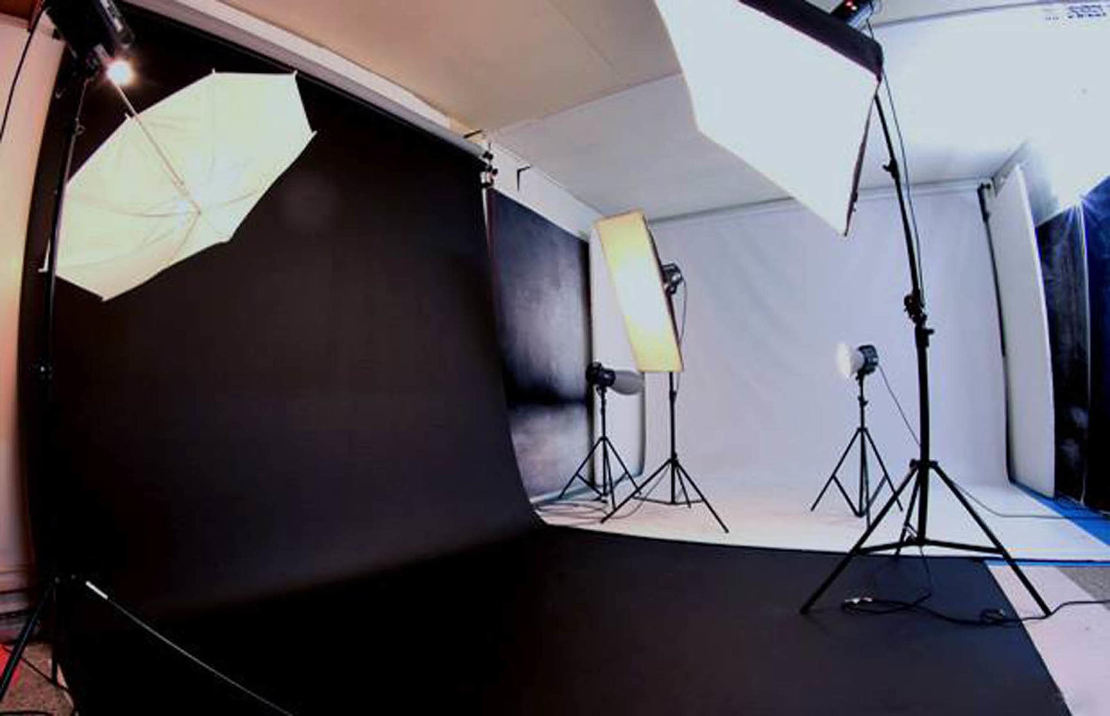 A photography studio setup with multiple lighting equipment and a dark backdrop.