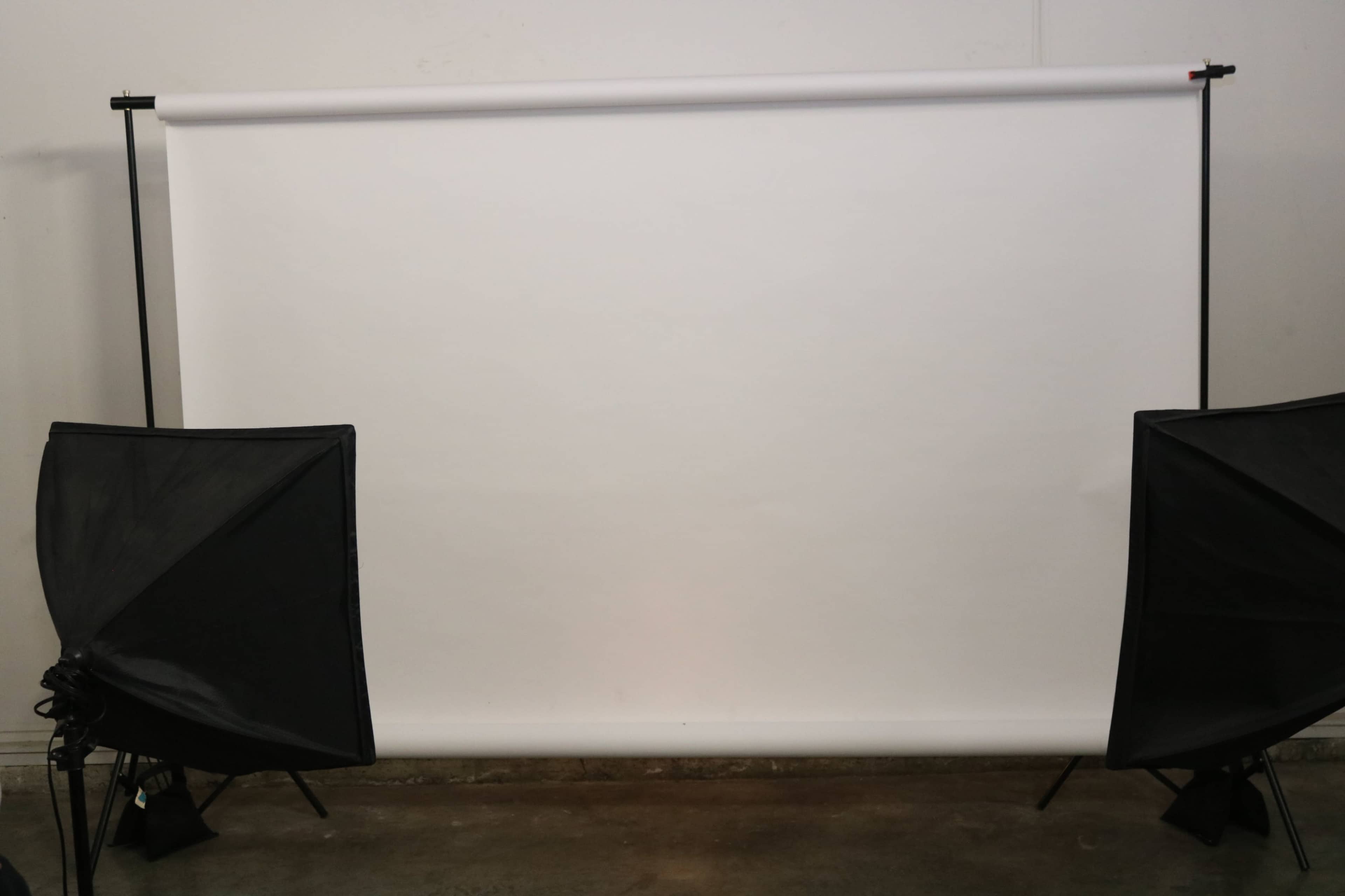 A blank white backdrop with two black softbox lighting setups on either side.