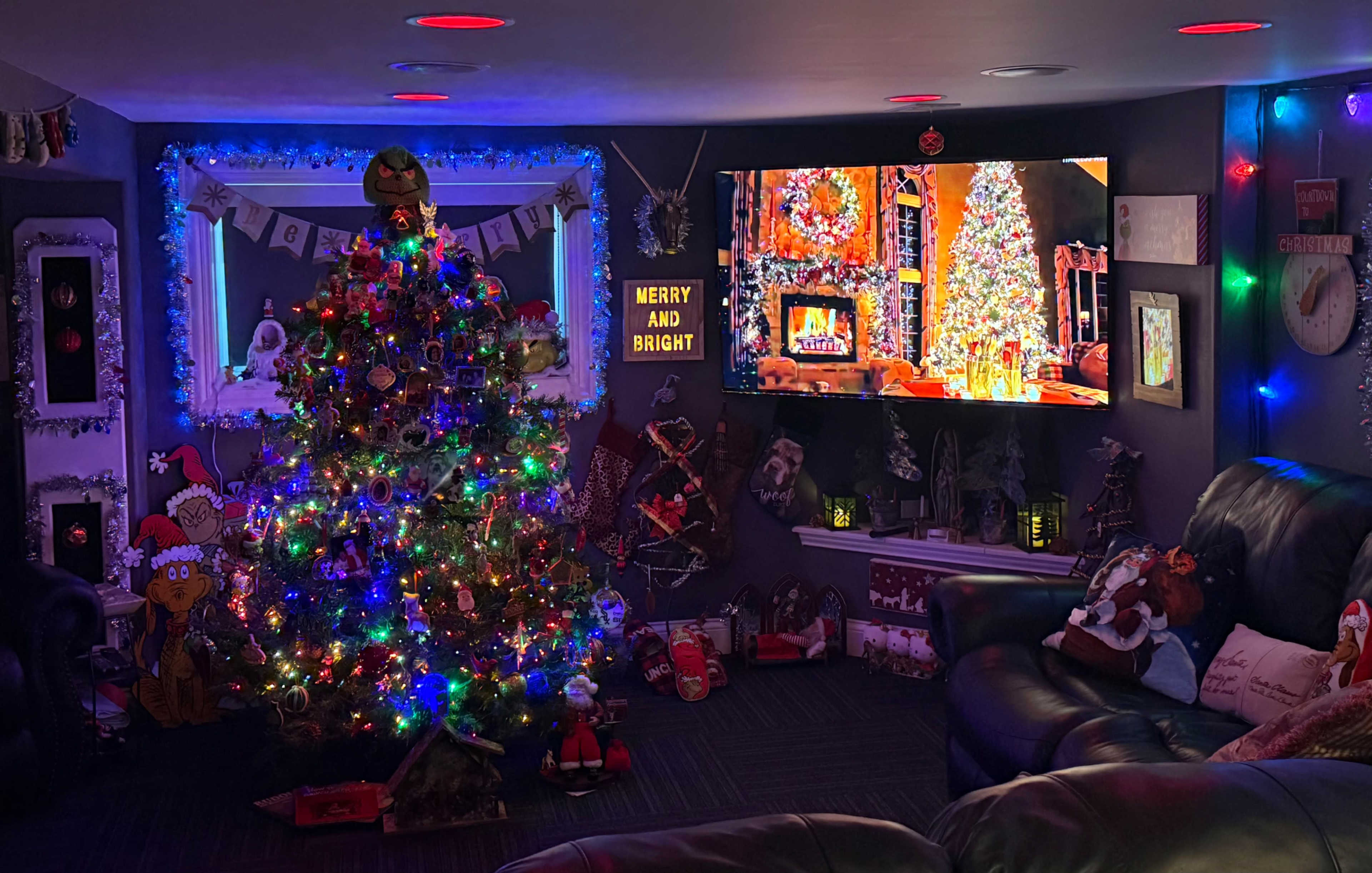 The image depicts a festively decorated room featuring a brightly lit Christmas tree, colorful ornaments, and a television displaying a holiday scene.
