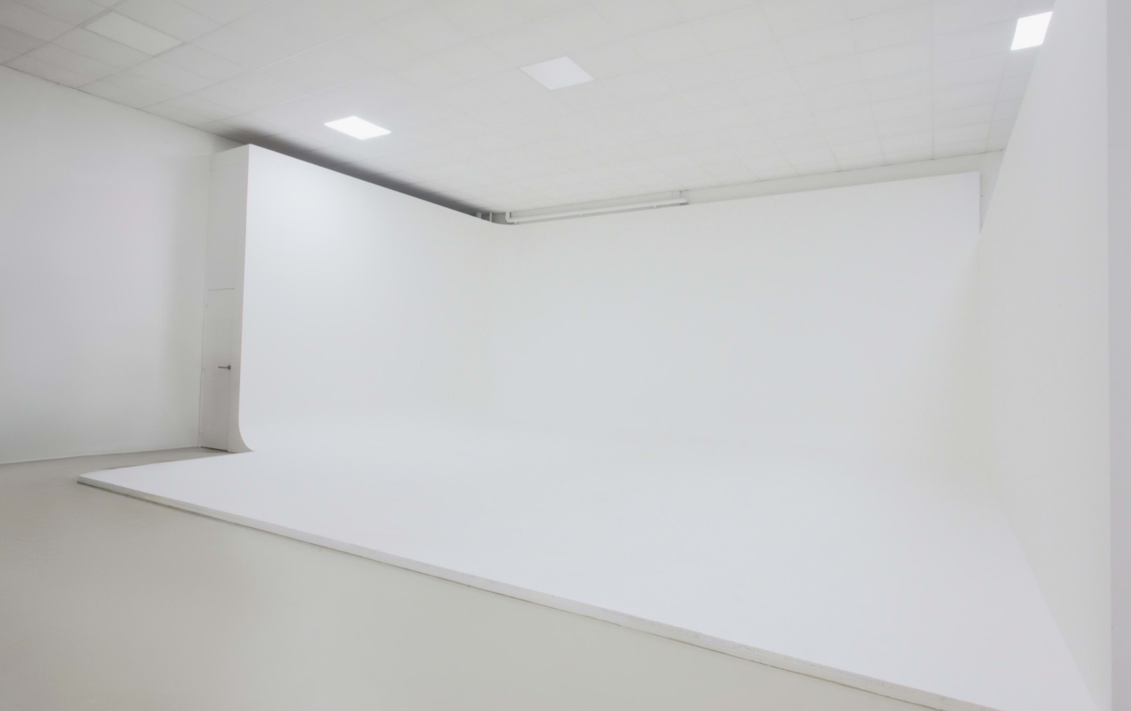 The image shows a spacious white studio with a seamless backdrop and plain flooring.