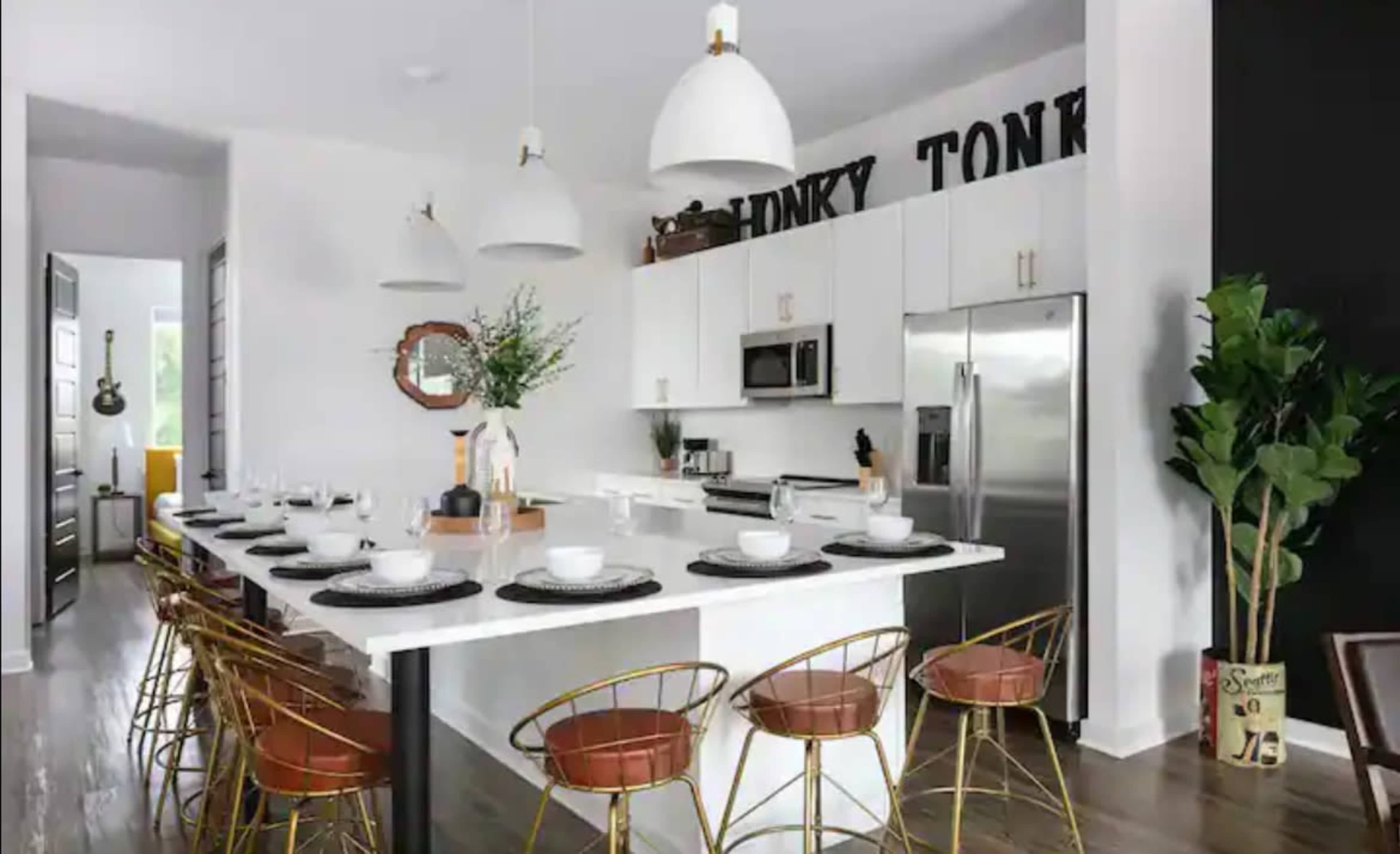 A modern kitchen features white cabinetry, stainless steel appliances, a large island with bar seating, and decorative elements on the walls.