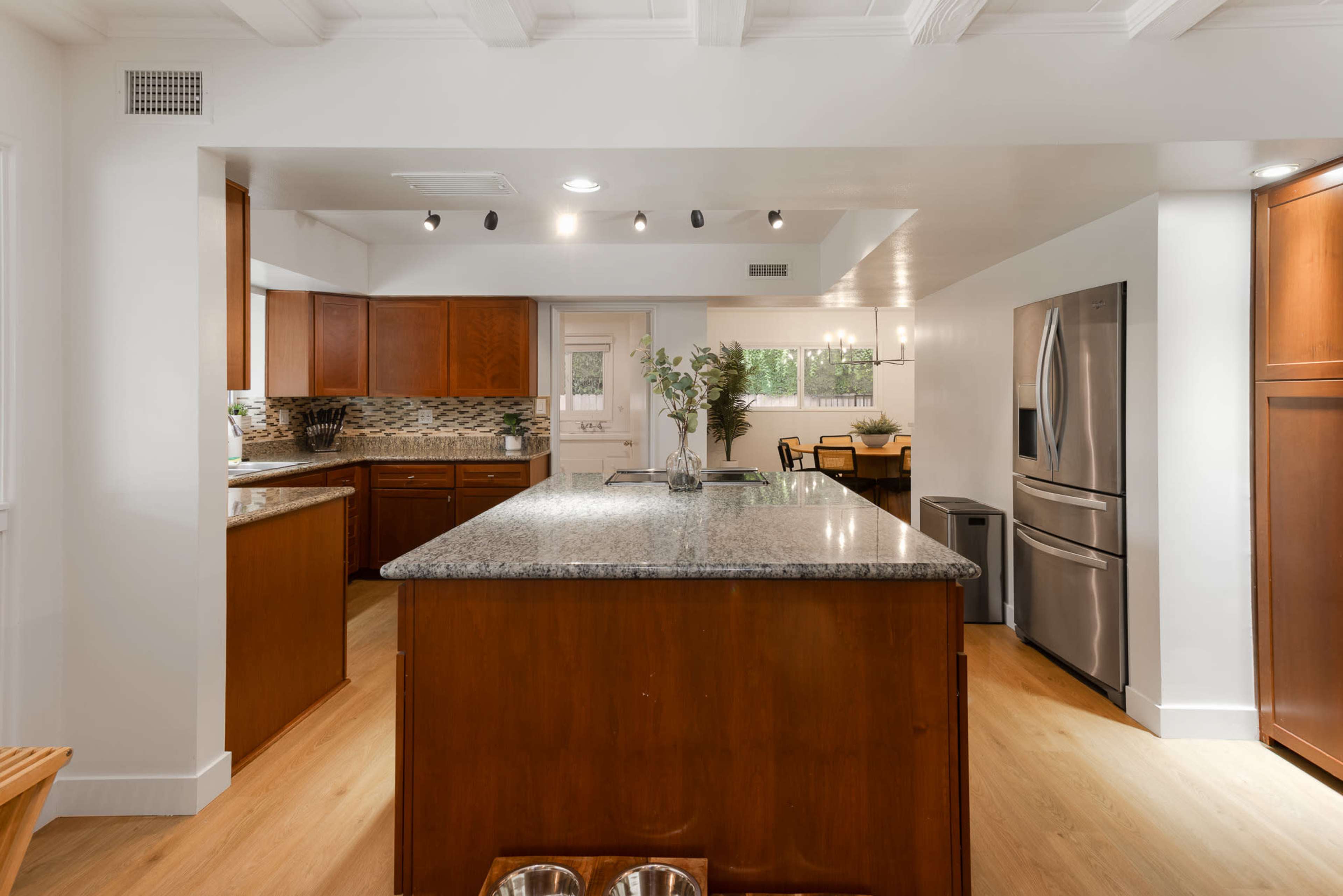 A spacious kitchen featuring wooden cabinets, a central island with a granite countertop, and stainless steel appliances.