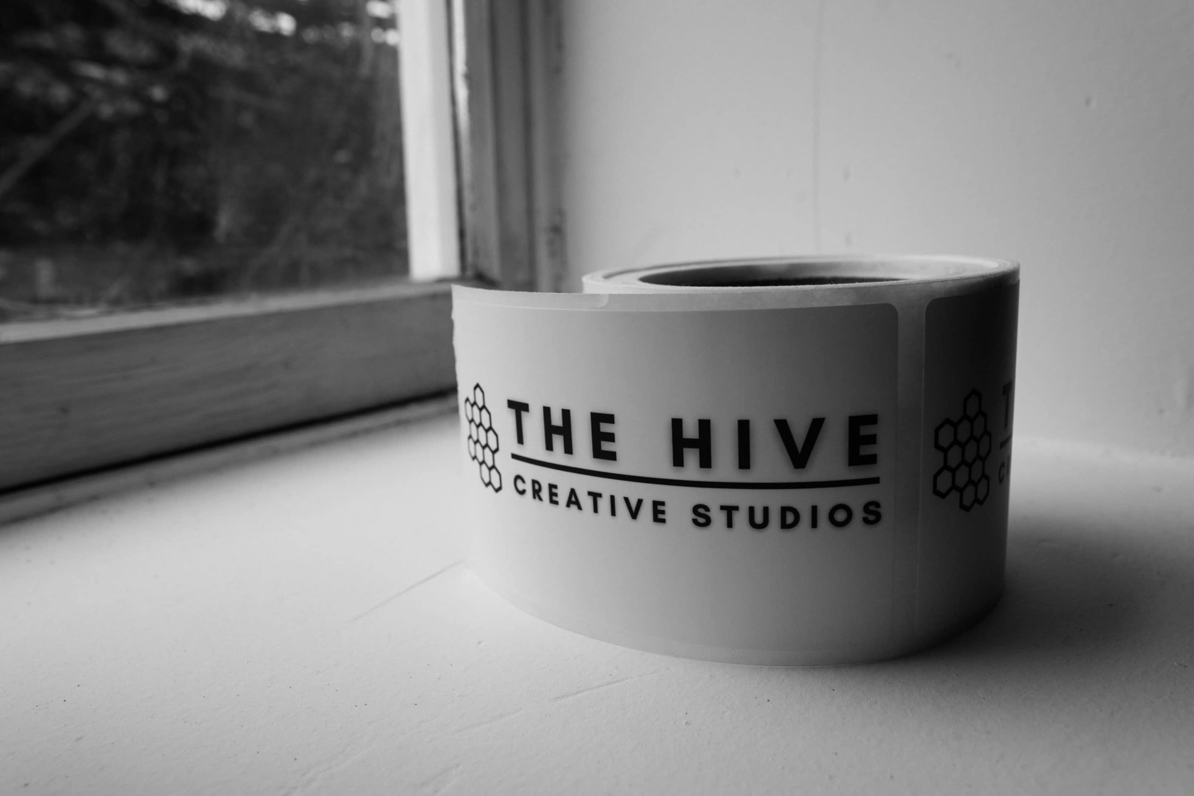 A roll of stickers labeled "THE HIVE CREATIVE STUDIOS" rests on a windowsill.