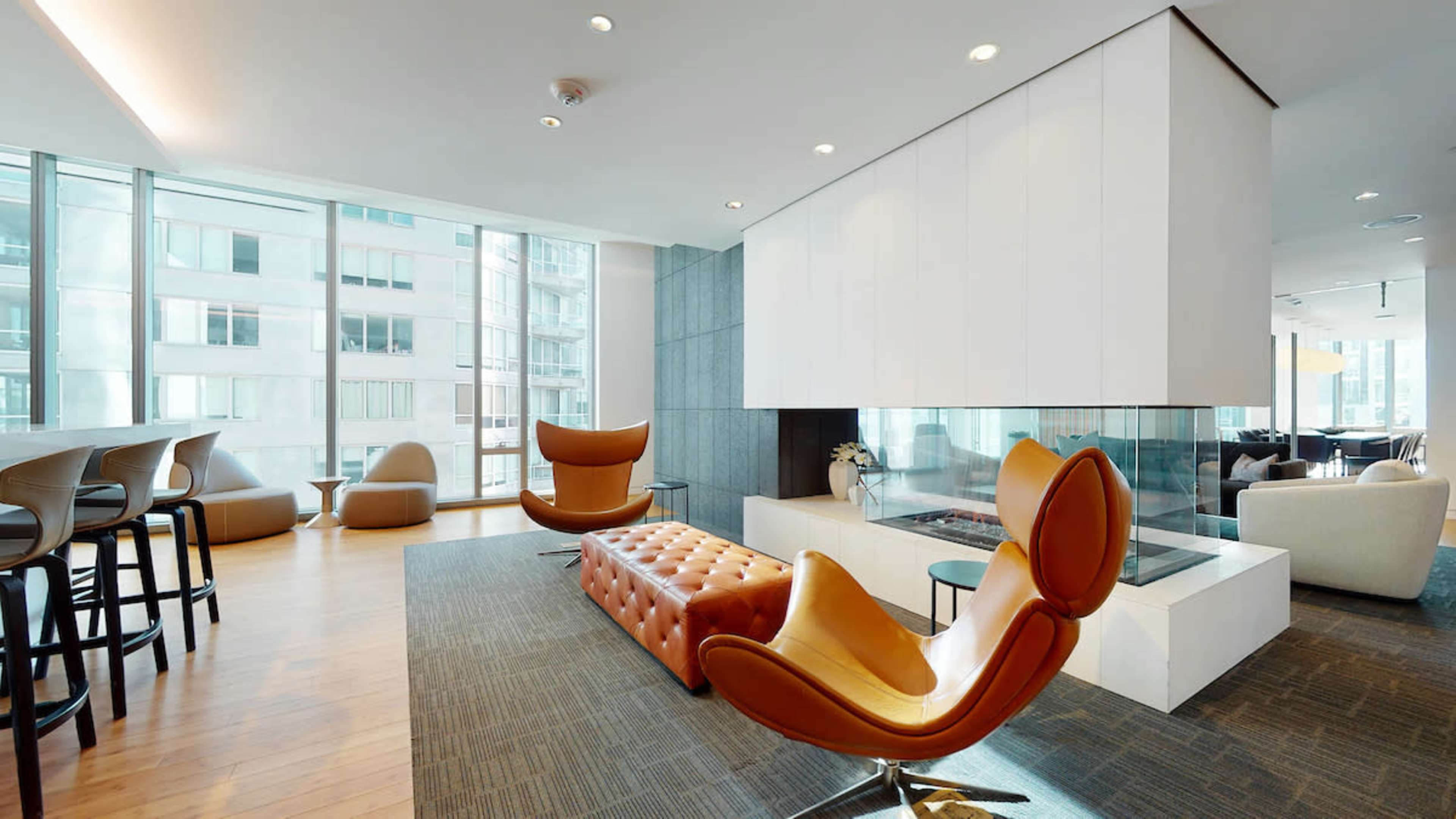 A modern interior space featuring a fireplace, stylish seating, and large windows that bring in natural light.