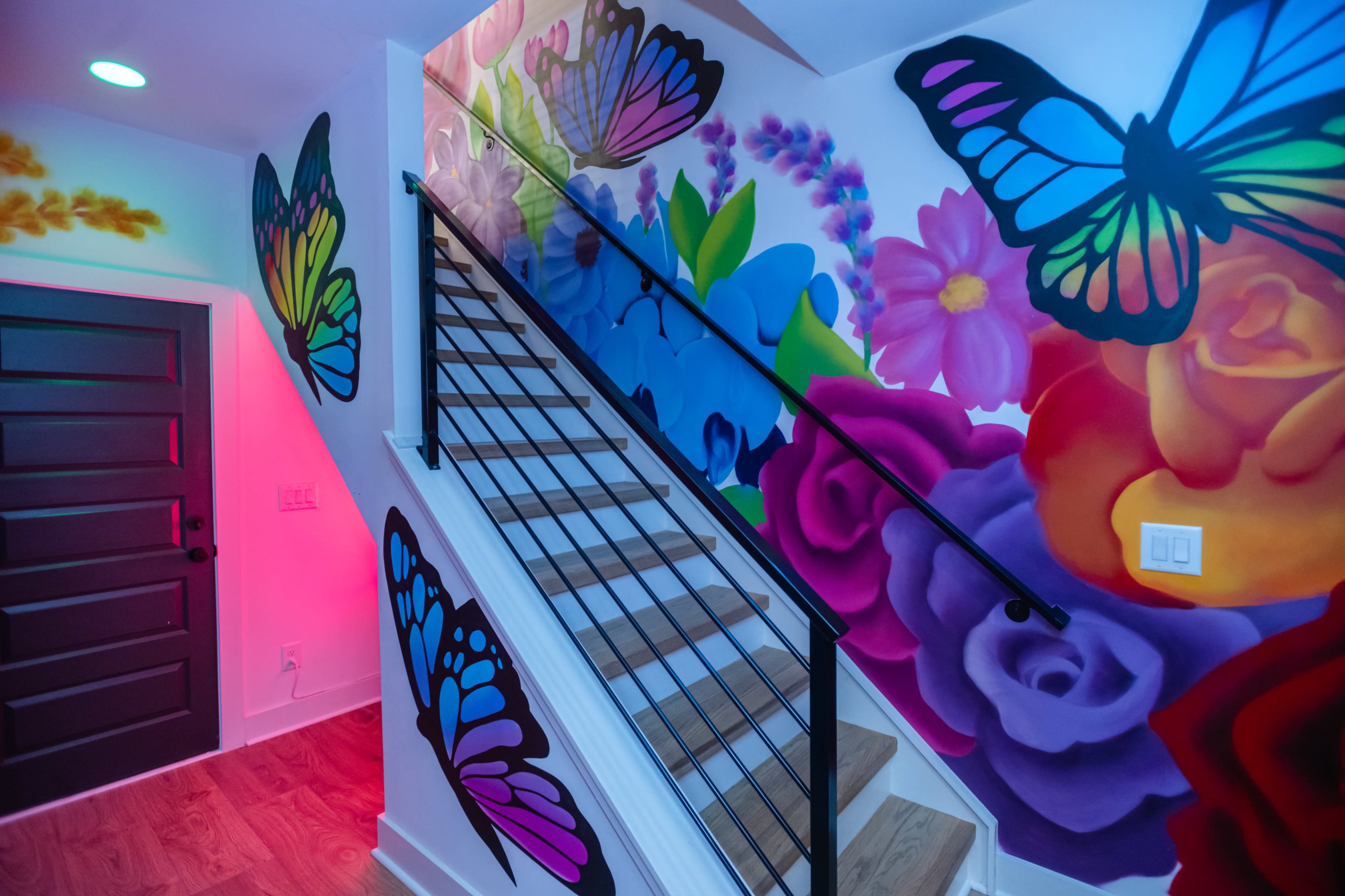 A brightly painted staircase with colorful murals of butterflies and flowers on the walls.