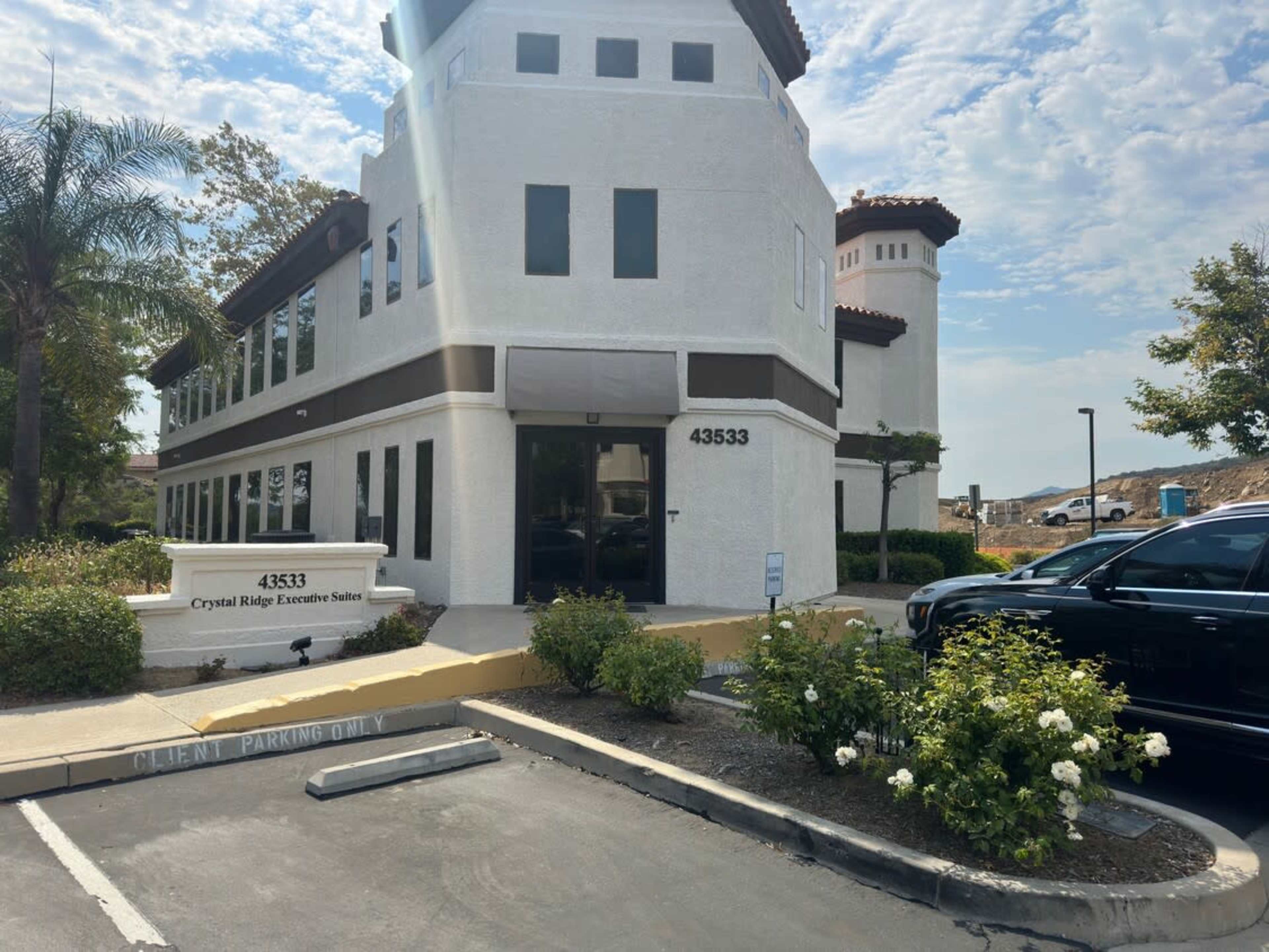 The image shows a two-story office building with a sign that reads "Crystal Ridge Executive Suites" and a parking area marked for client parking.