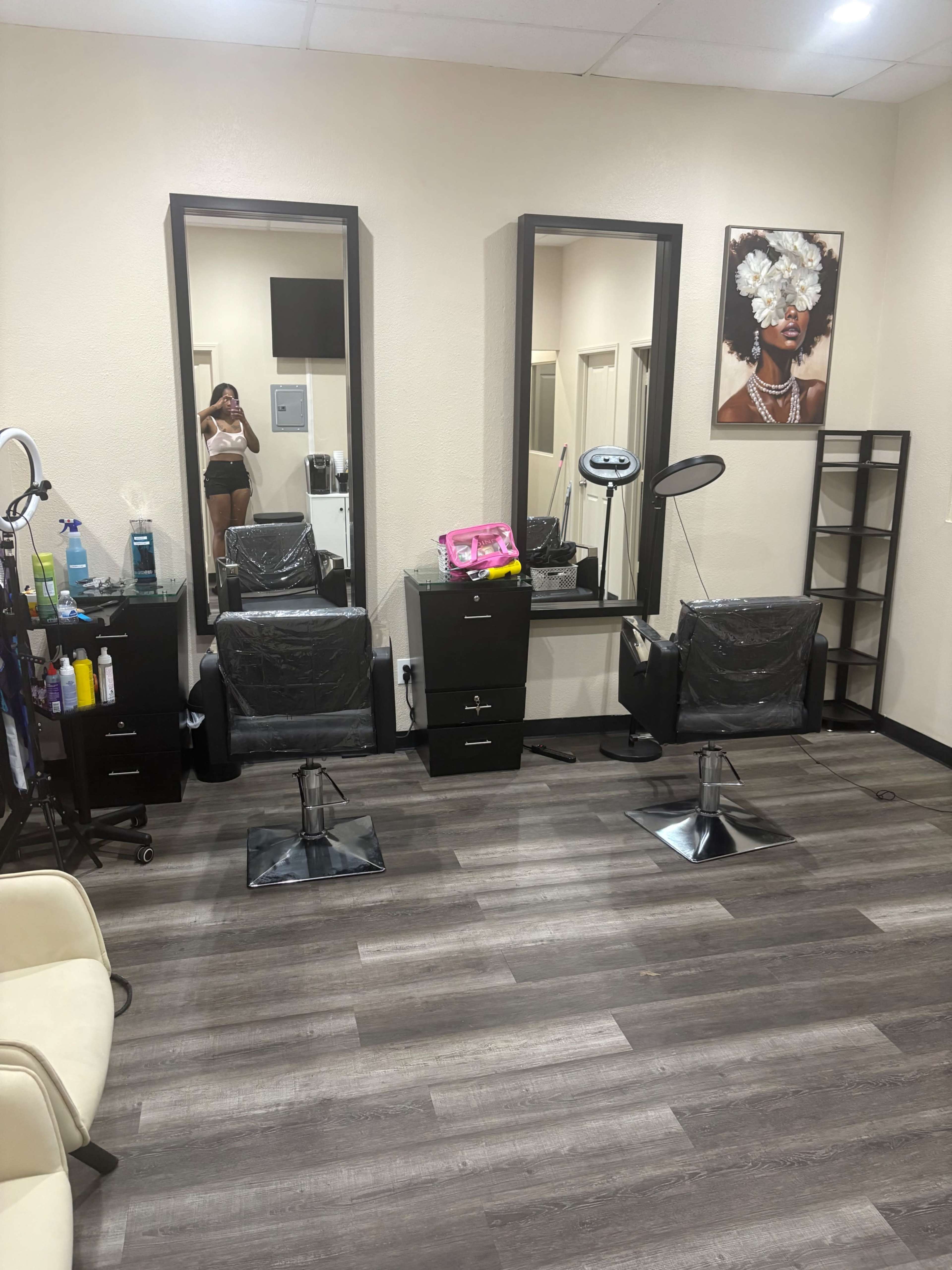 The image shows a hair salon interior with two styling chairs, large mirrors, and various salon equipment neatly arranged on the floor and shelves.