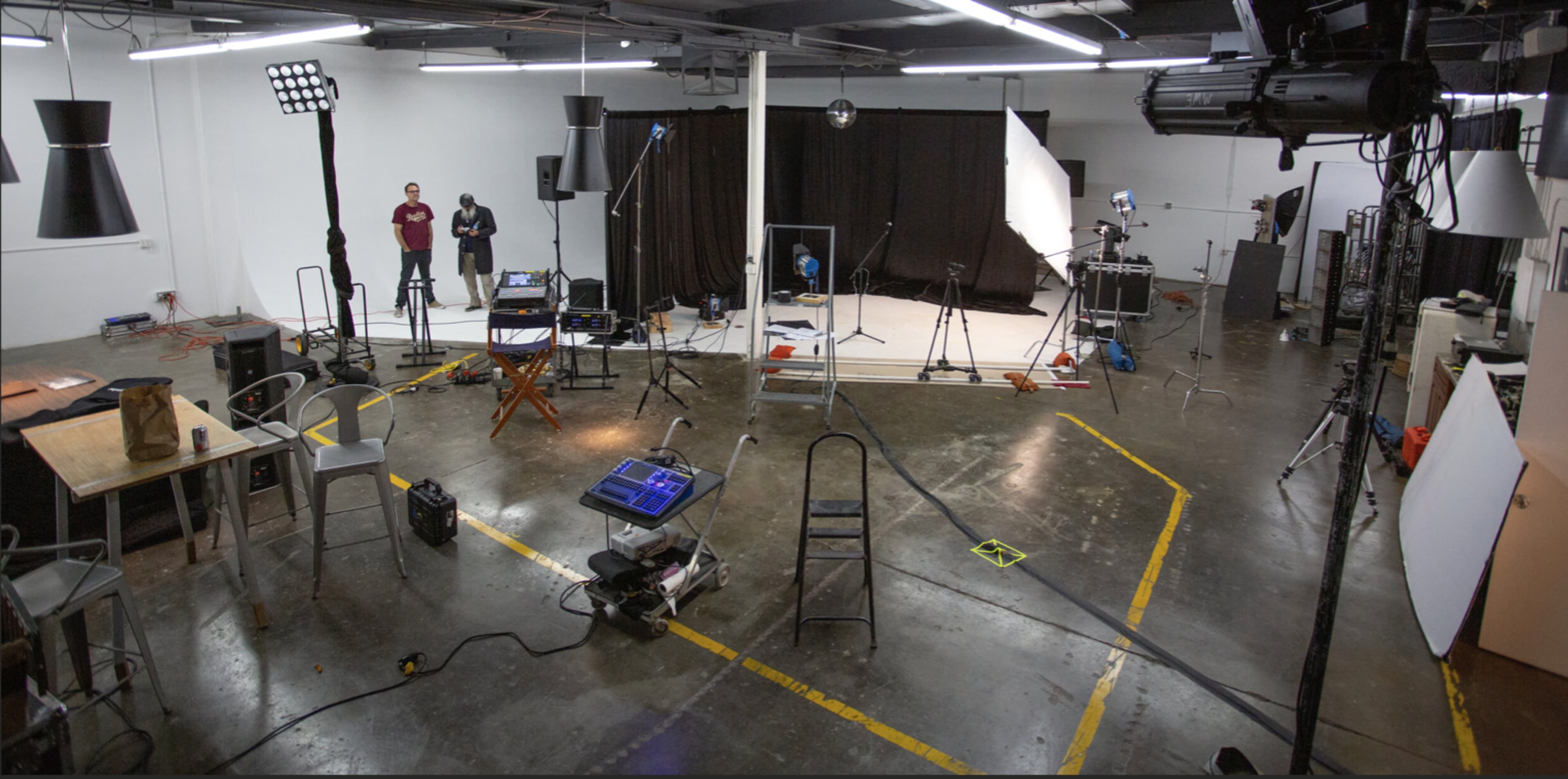 A studio space set up for a photoshoot, with lights, backdrops, and various equipment scattered throughout the area.