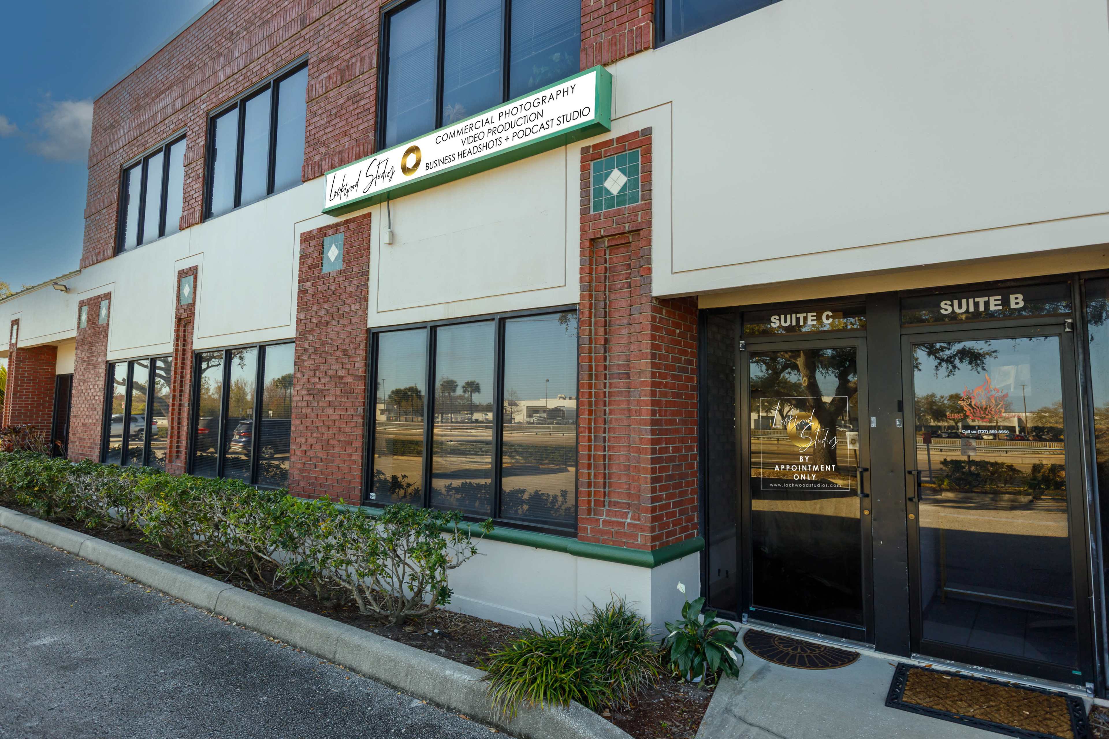 The image shows the exterior of a commercial building featuring large windows, a sign for a photography studio, and a door labeled "Suite B."