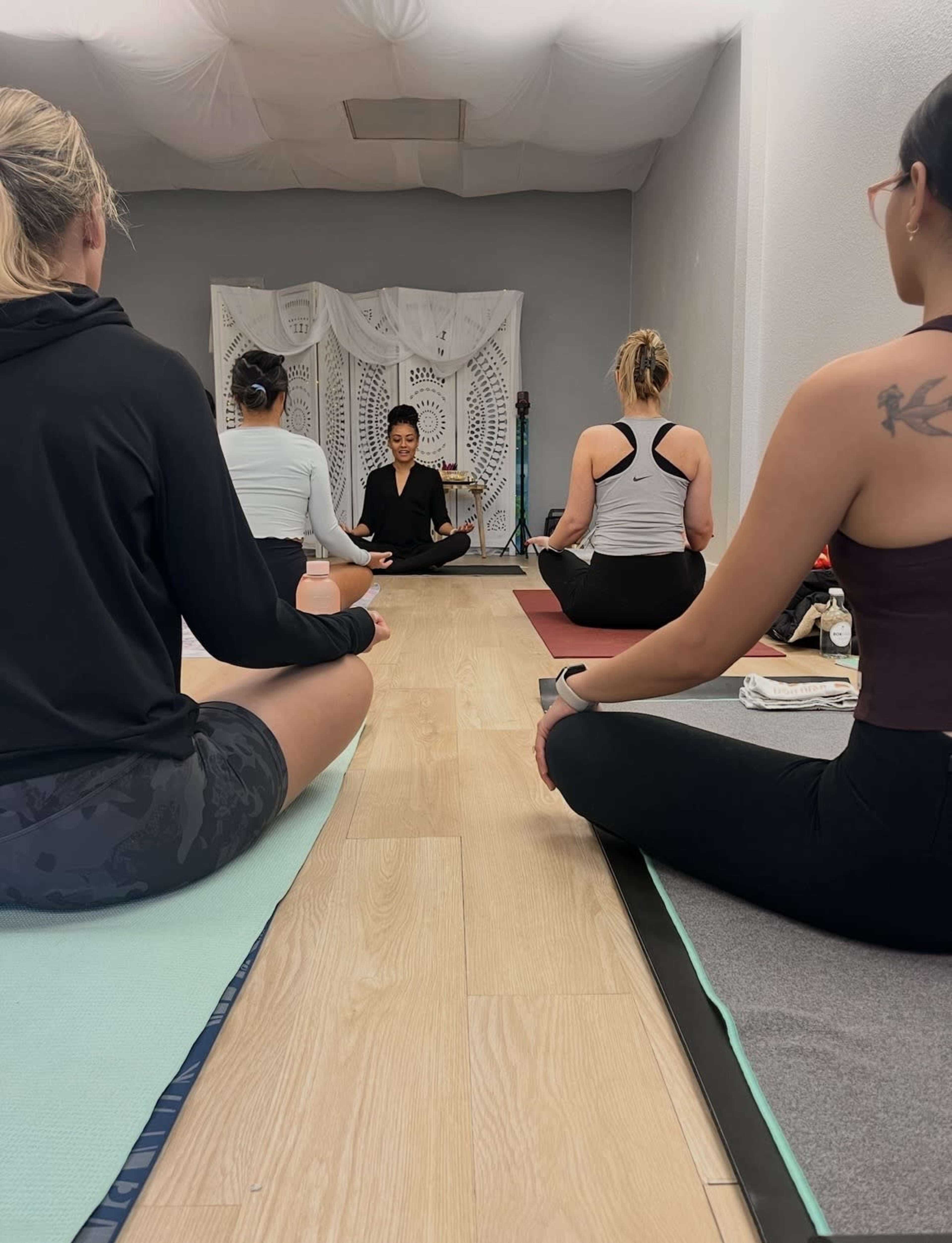 A group of individuals practice meditation in a serene indoor space.