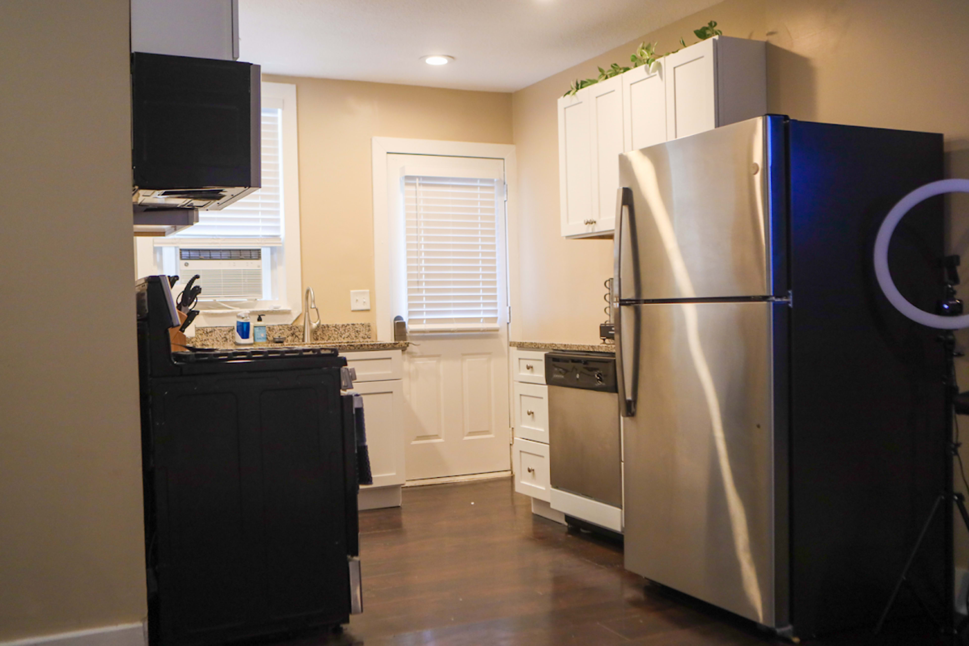 A compact kitchen featuring stainless steel appliances, dark cabinetry, and a window above the sink.