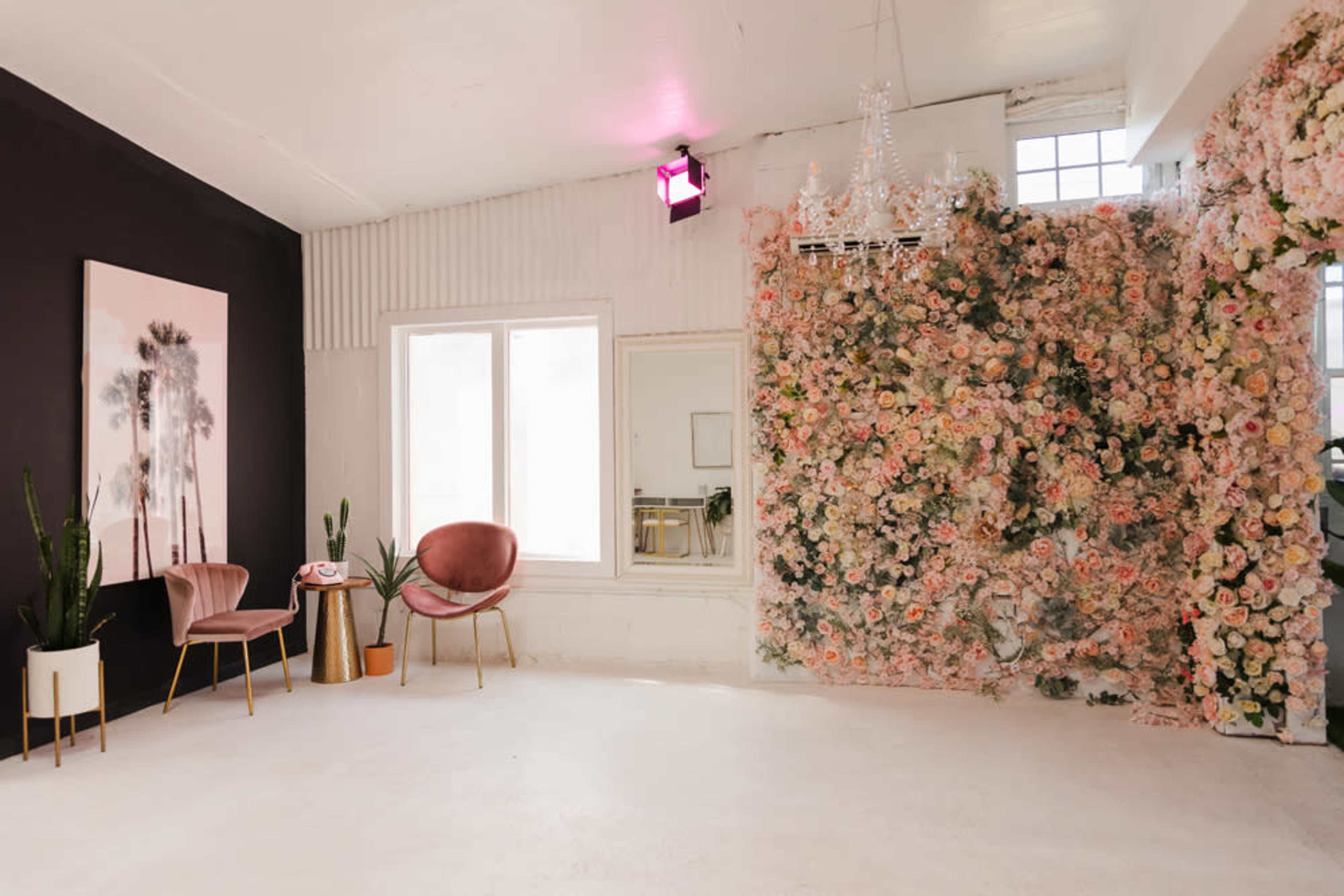A modern interior space with a floral wall, decorative chairs, and large windows.