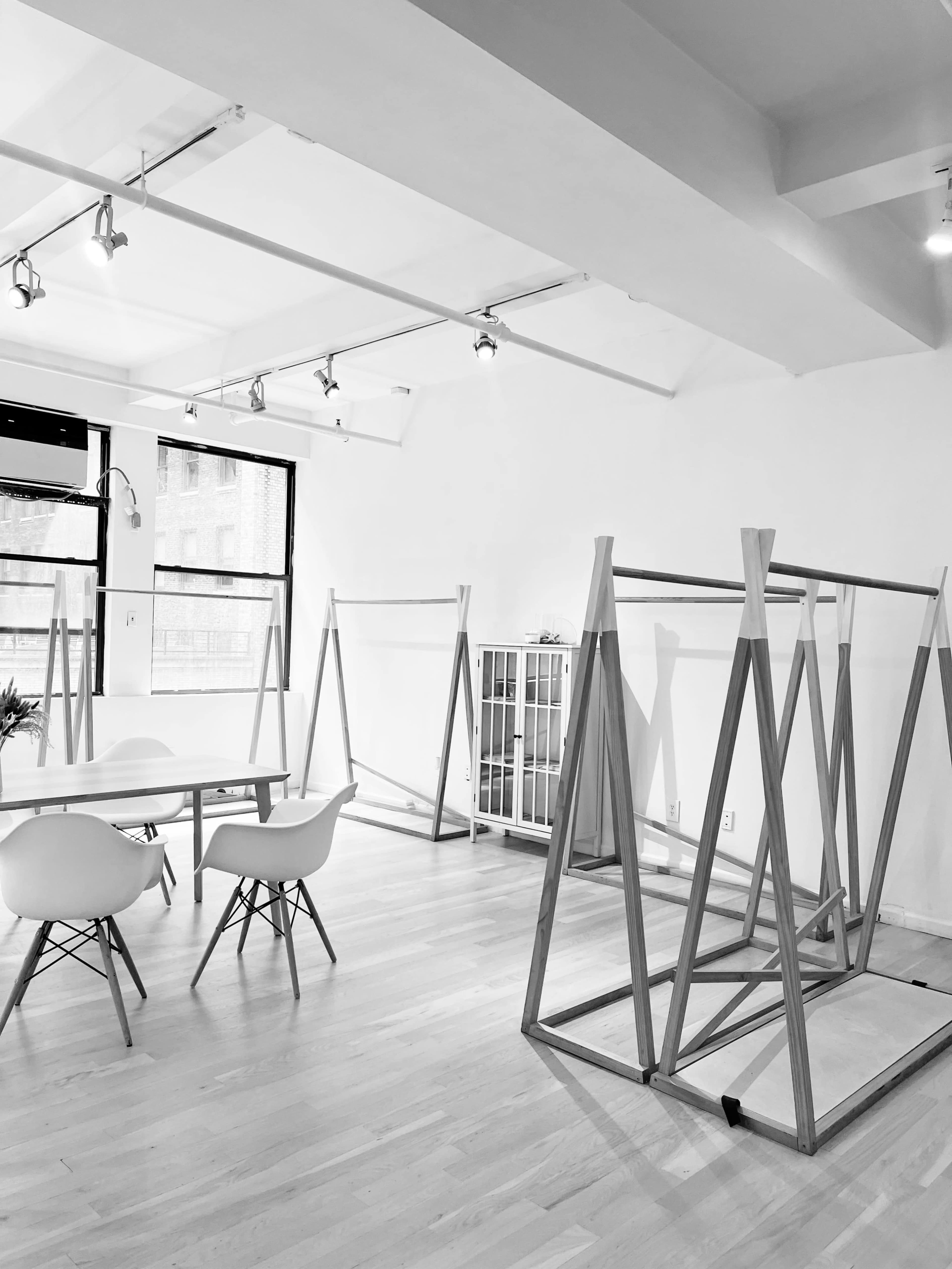 A spacious room with wooden frames in the center and a table with chairs on one side.