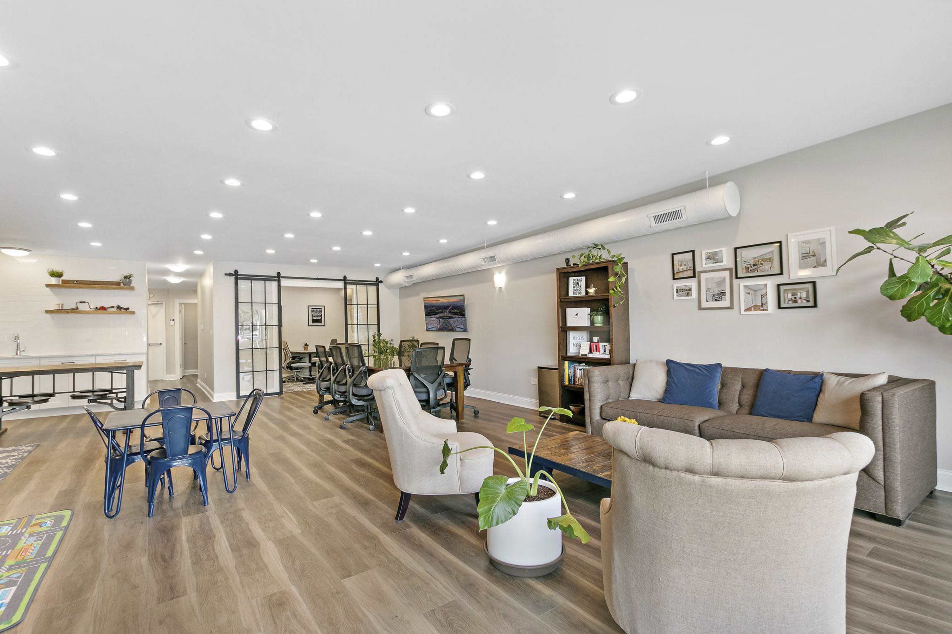 A modern, open-concept office space with a seating area, desks, and a child's play area.
