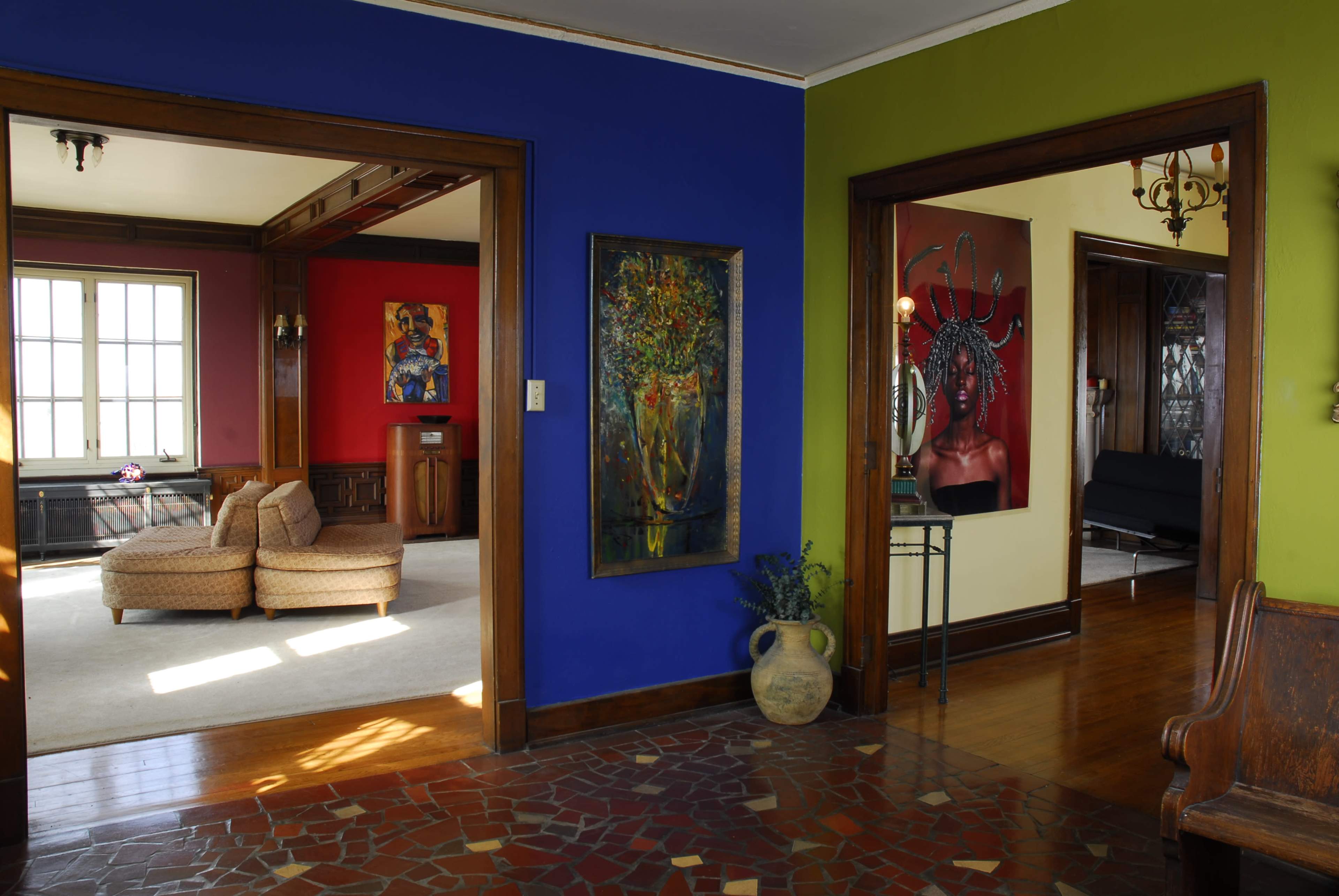 A spacious interior with colorful walls in blue, green, and red, divided by open doorways leading to different living areas.