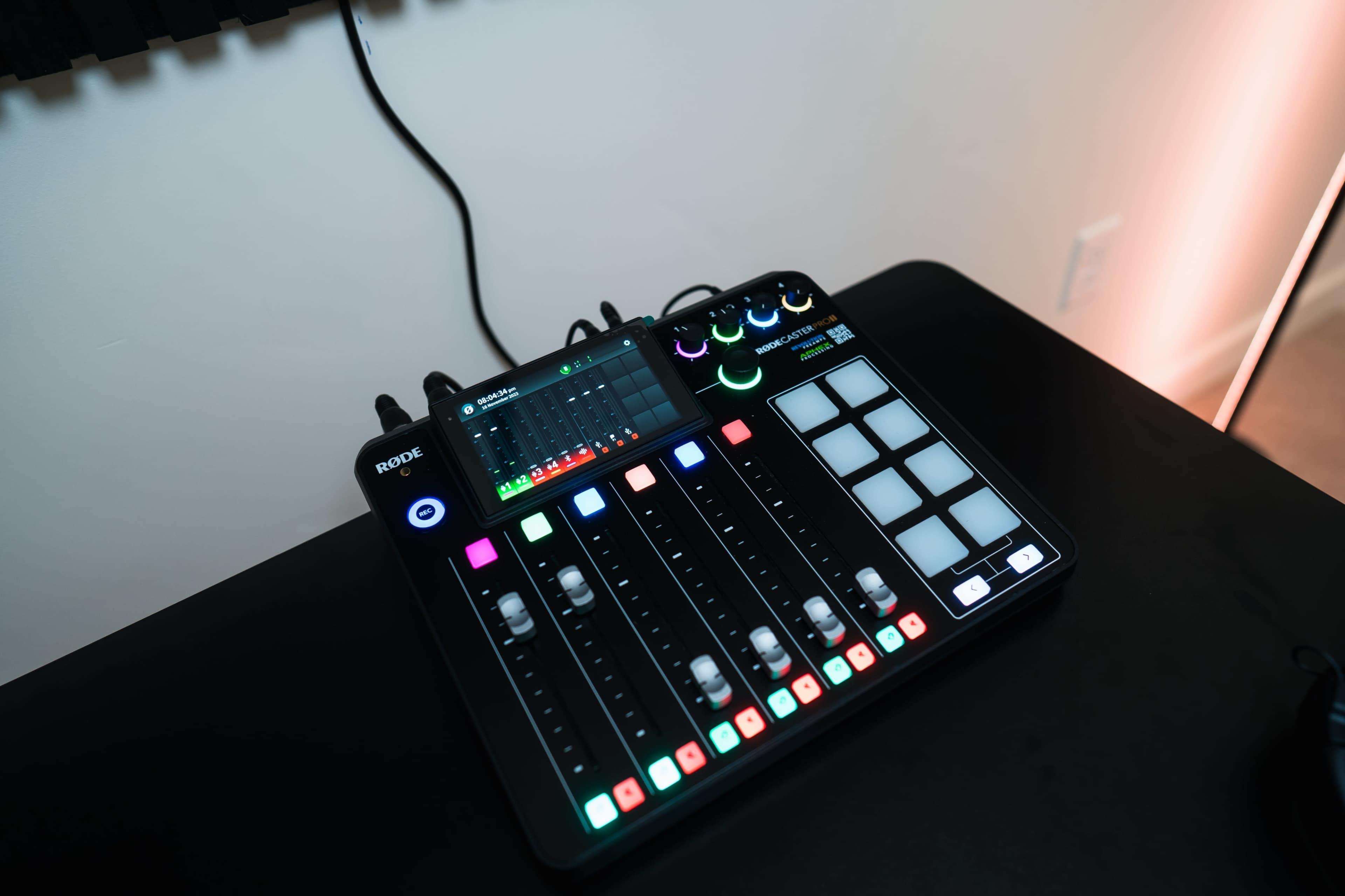 A multi-channel audio interface with sliders, buttons, and LED indicators arranged on a black surface.
