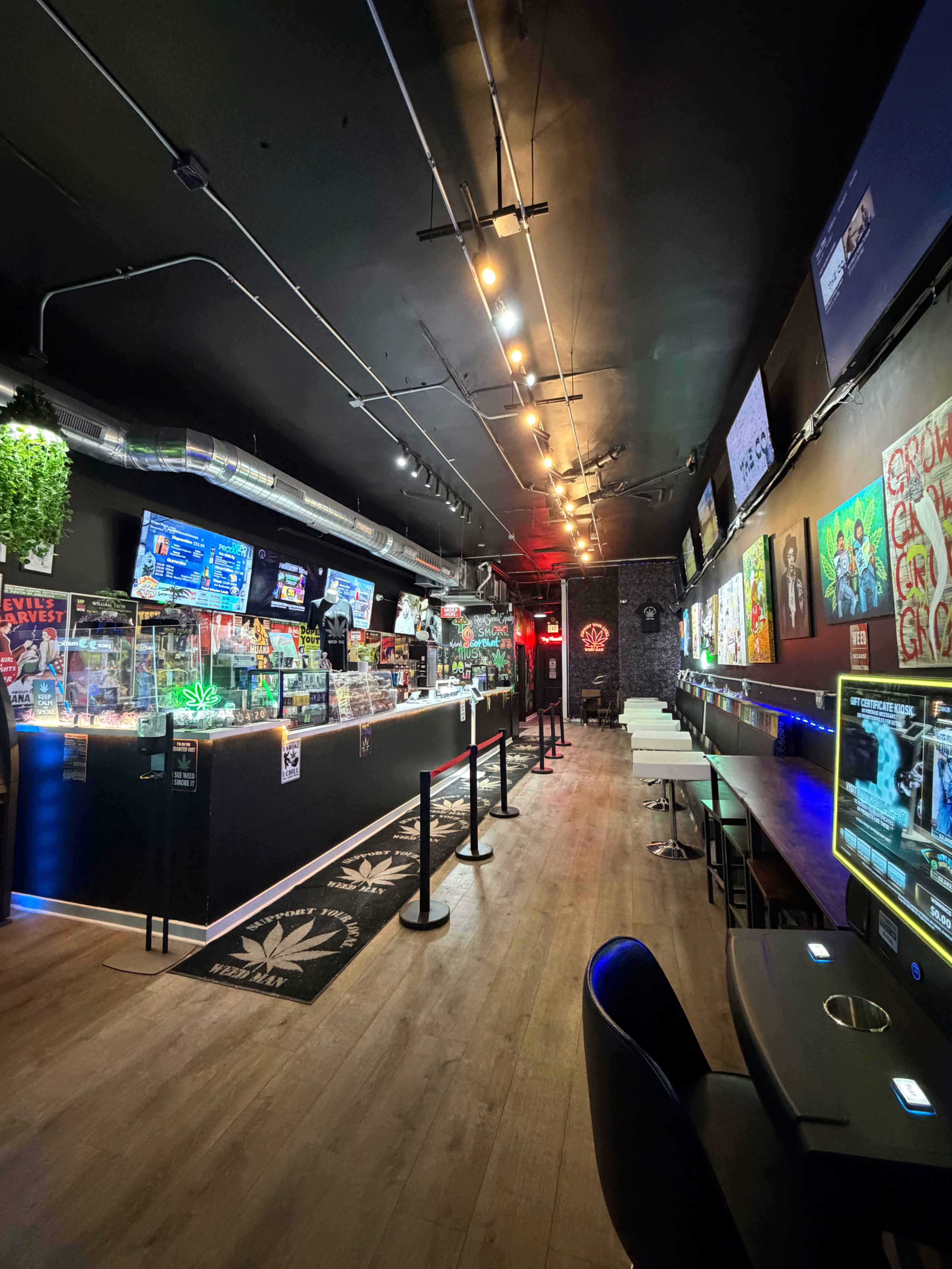 The image shows a dimly lit arcade filled with video game machines, colorful artwork on the walls, and a counter lined with game displays.
